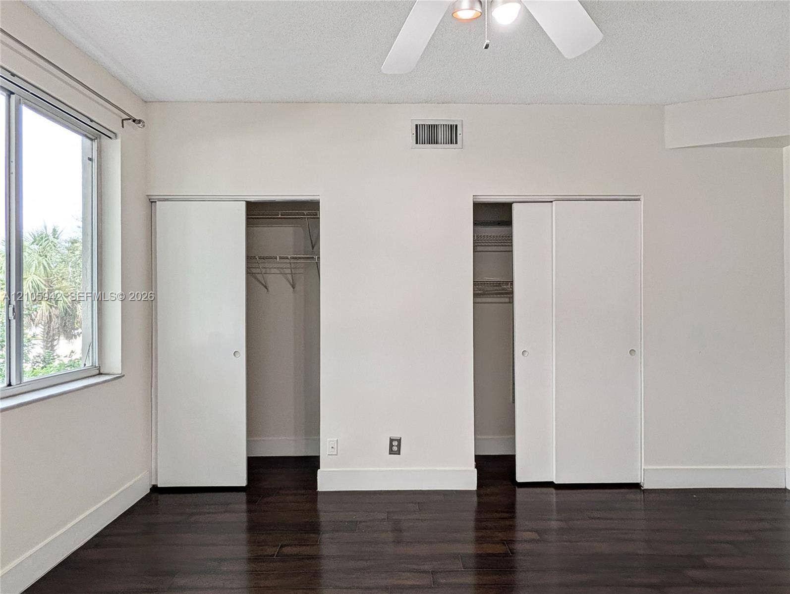 271 Duval Court, Weston, Weston, FL 33326 Dark wood-finish flooring, dual closets with sliding panel doors, ceiling fan with integrated lighting, and a window with exterior greenery