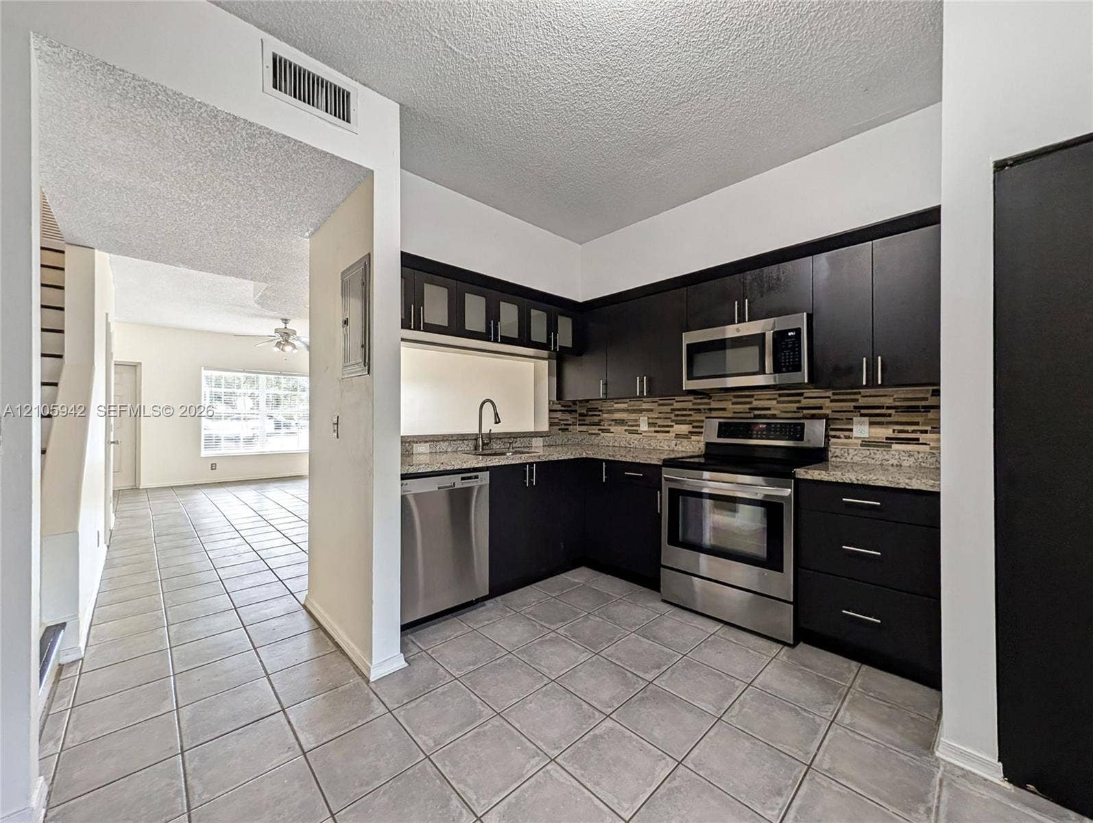 271 Duval Court, Weston, Weston, FL 33326 Kitchen featuring dark cabinetry, stone-finish countertops, stainless steel appliances, a multi-tone tile backsplash, and ceramic floor tiling