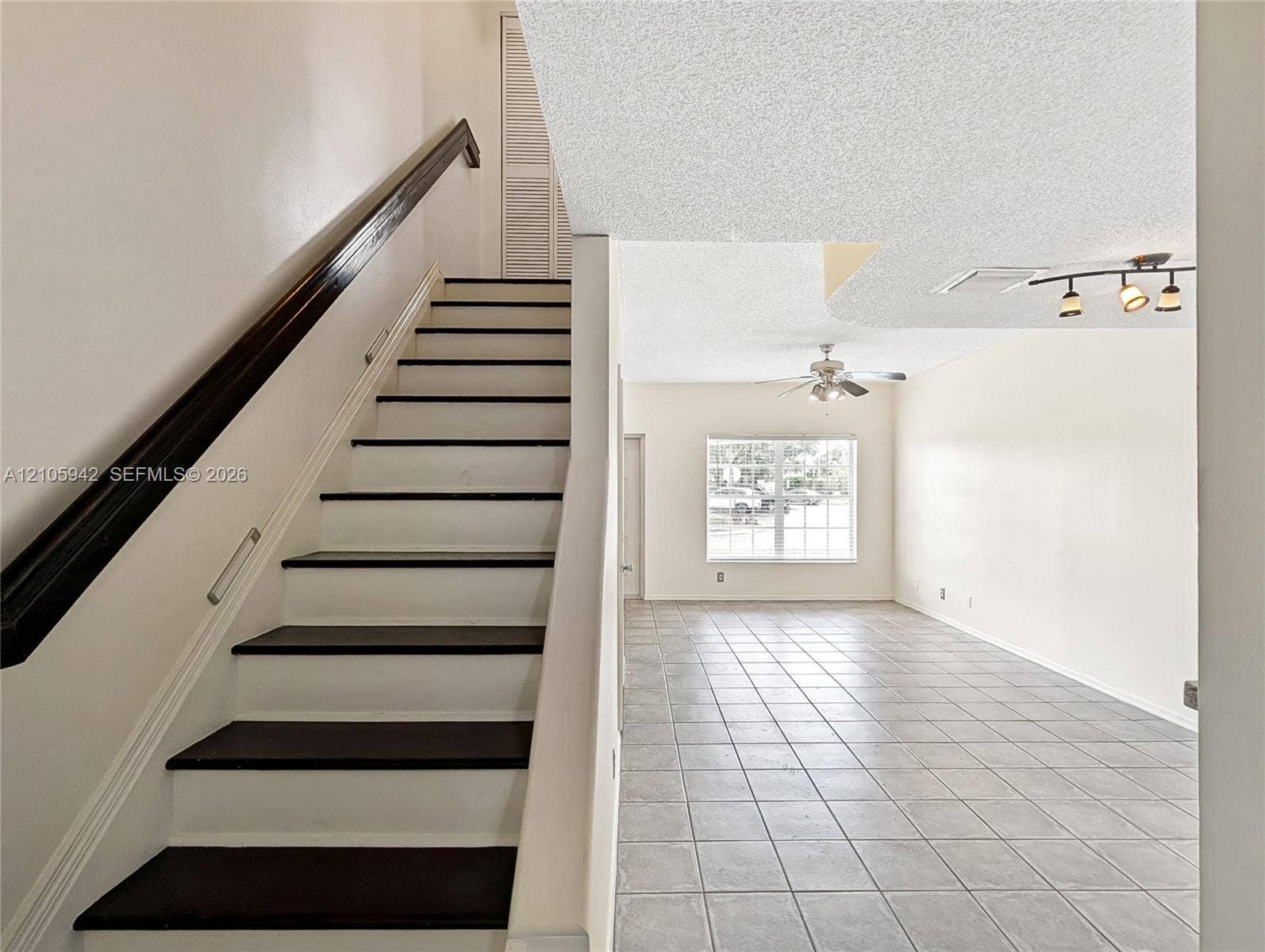 271 Duval Court, Weston, Weston, FL 33326 Staircase featuring dark wood-finish treads and a high-contrast railing, complemented by ceramic tile flooring, a ceiling fan, and multi-light track lighting