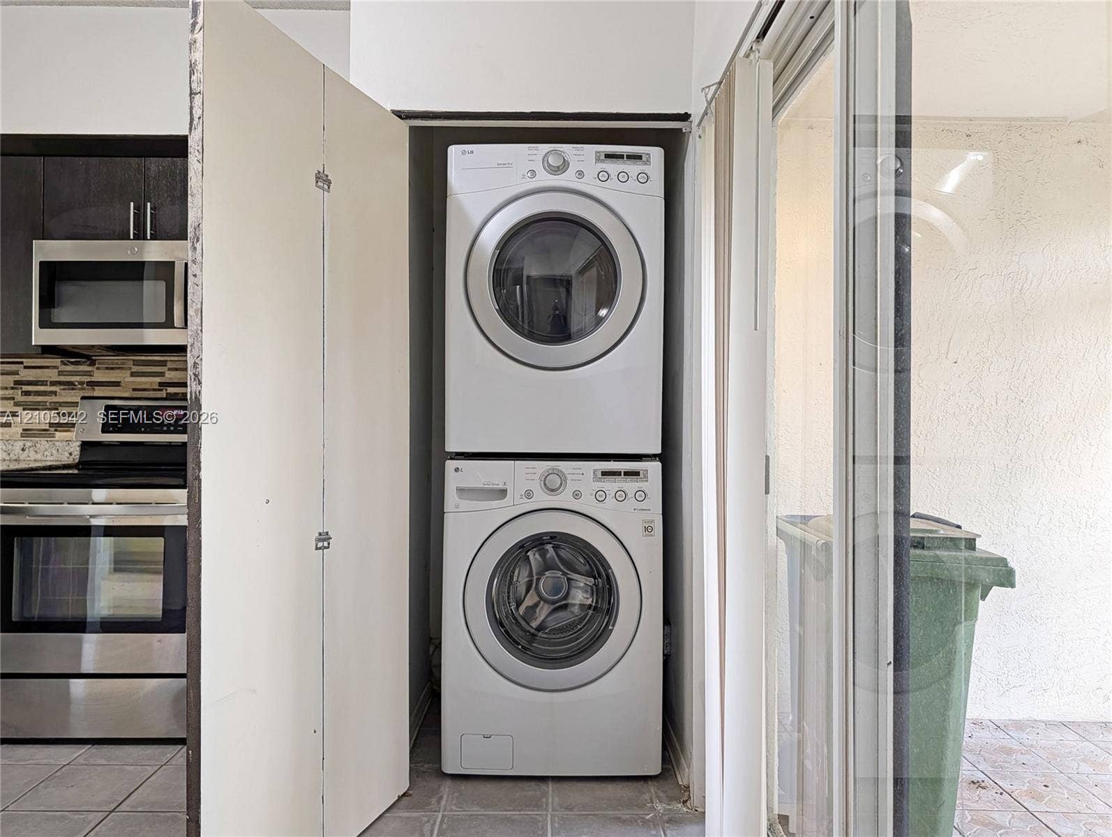 271 Duval Court, Weston, Weston, FL 33326 Stacked washer and dryer unit, stainless steel microwave, stainless steel range, and tile flooring