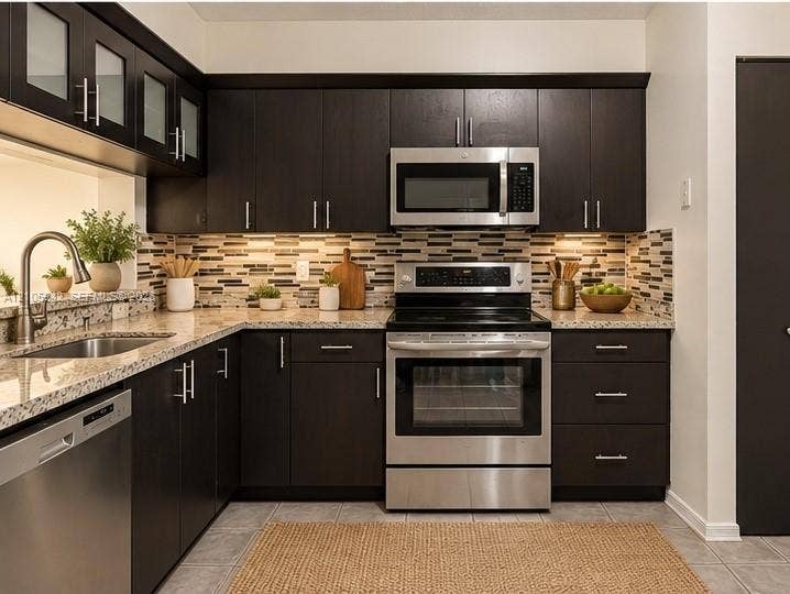 271 Duval Court, Weston, Weston, FL 33326 Staged-Kitchen featuring dark wood cabinetry, stainless steel appliances, multi-tonal tile backsplash, stone-finish countertops, and an undermount sink