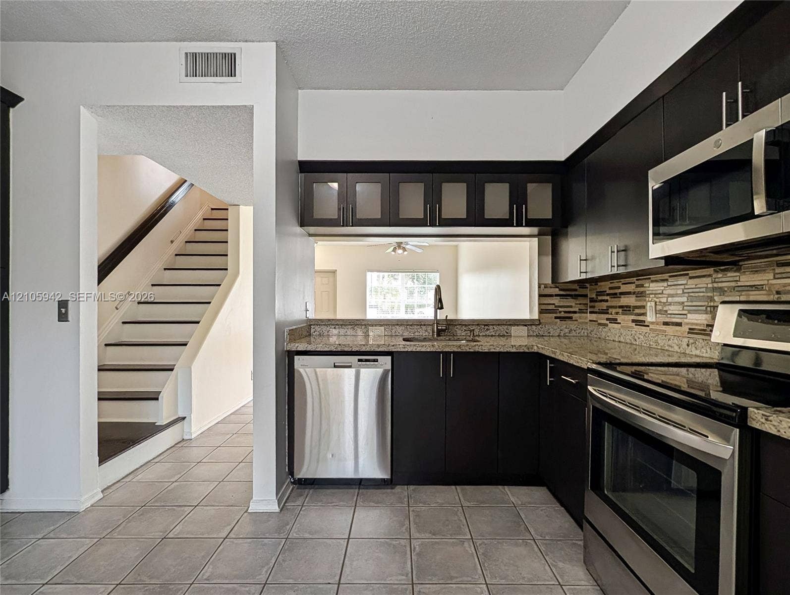 271 Duval Court, Weston, Weston, FL 33326 Kitchen featuring dark cabinetry, stone-finish countertops, stainless steel appliances, a glass-tile backsplash, and tiled flooring