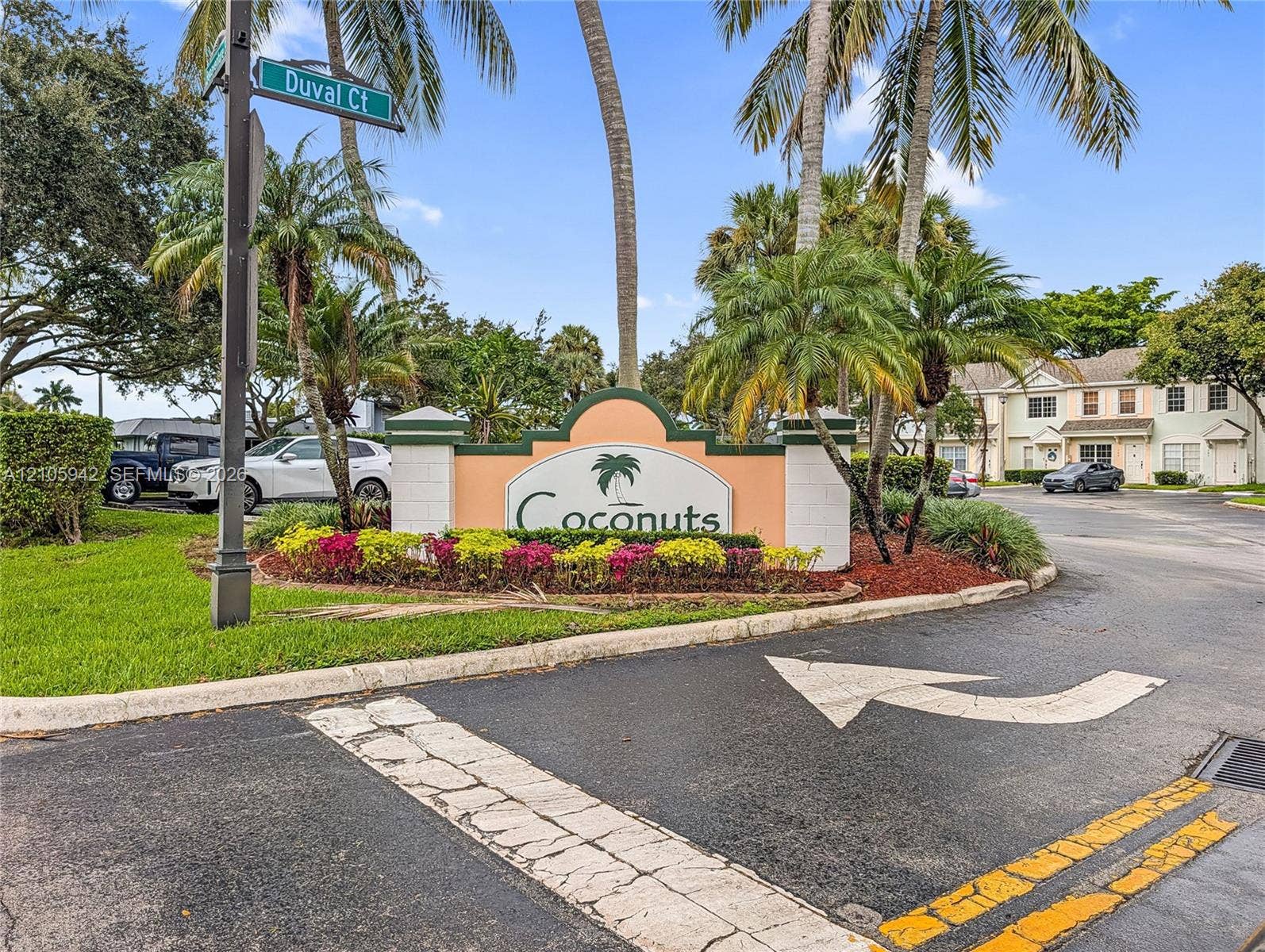 271 Duval Court, Weston, Weston, FL 33326 Community entrance sign featuring masonry pillars, integrated landscaping, mature palm trees, and asphalt roadway