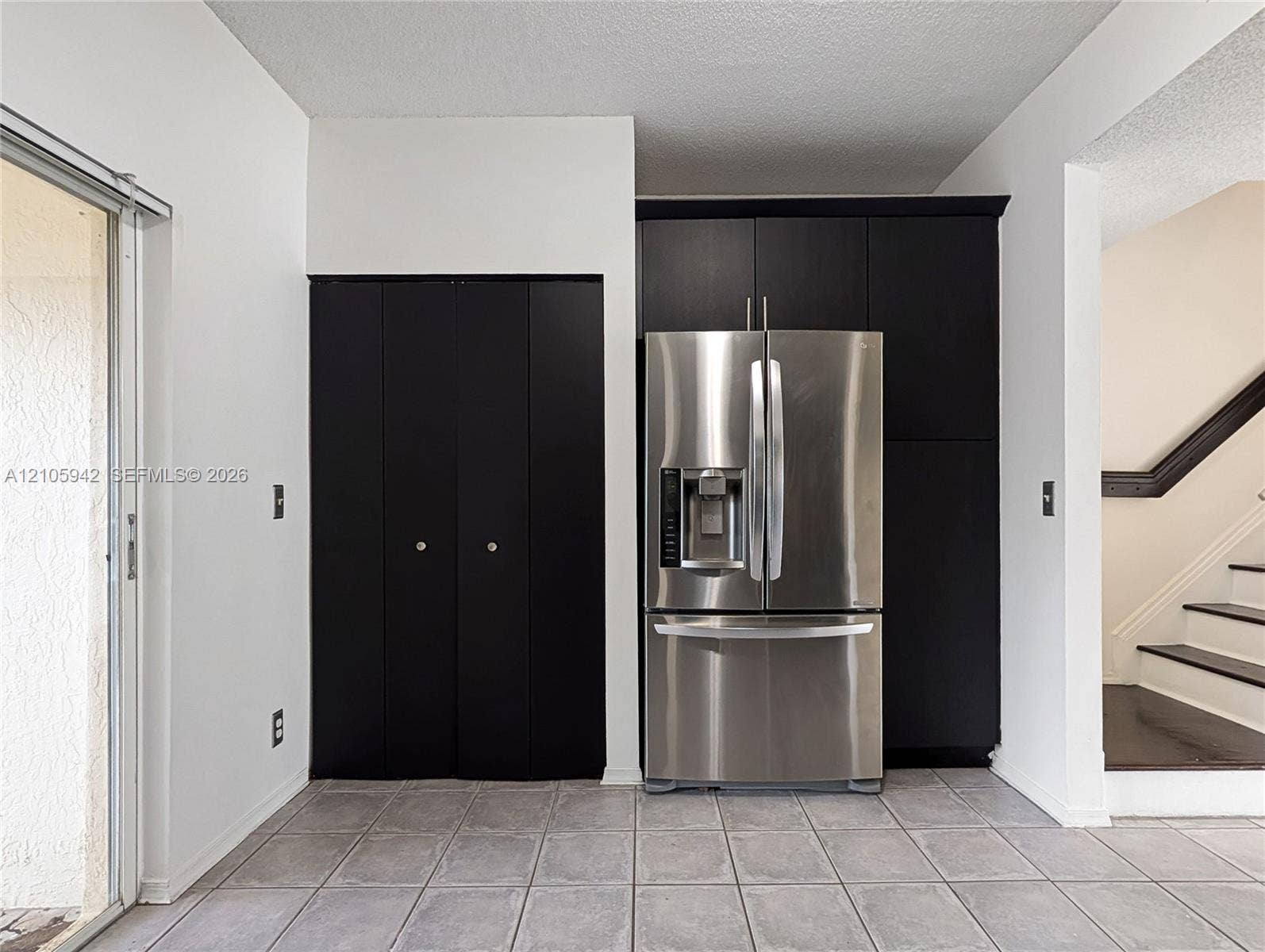 271 Duval Court, Weston, Weston, FL 33326 Dark-toned built-in cabinetry, stainless steel French-door refrigerator, tile flooring, and sliding glass door
