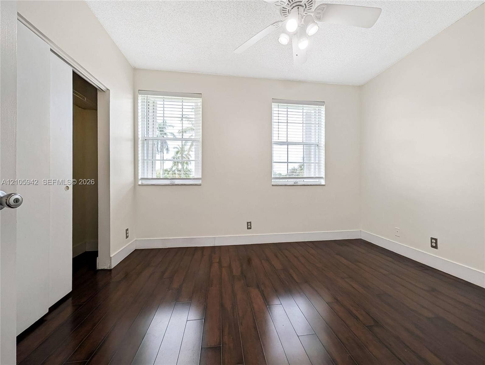 271 Duval Court, Weston, Weston, FL 33326 Room featuring dark-toned wood-finish flooring, two windows with horizontal blinds, and a white ceiling fan with integrated lighting