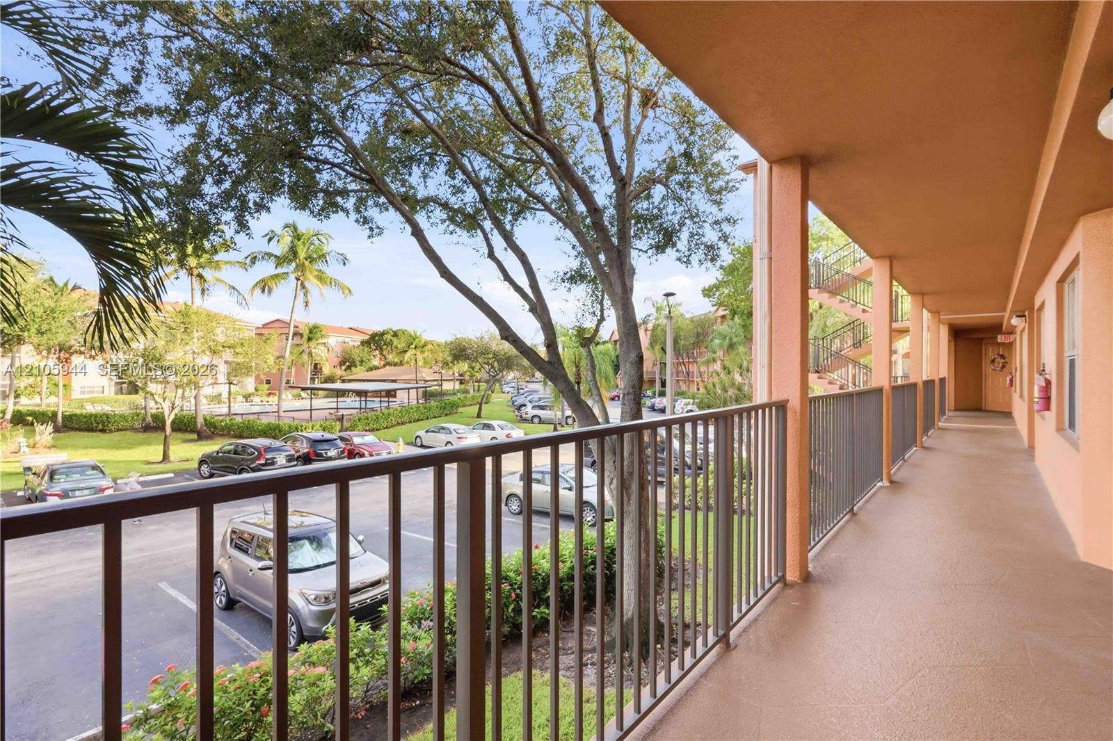 Covered exterior walkway featuring a concrete floor, metal railings, and stucco exterior walls