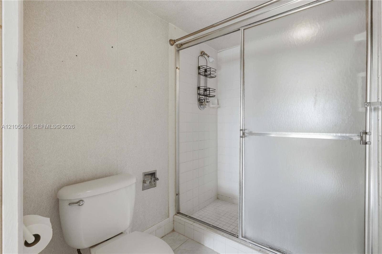 Full bathroom featuring a glass-enclosed shower stall with tiled interior, white toilet, and tile flooring
