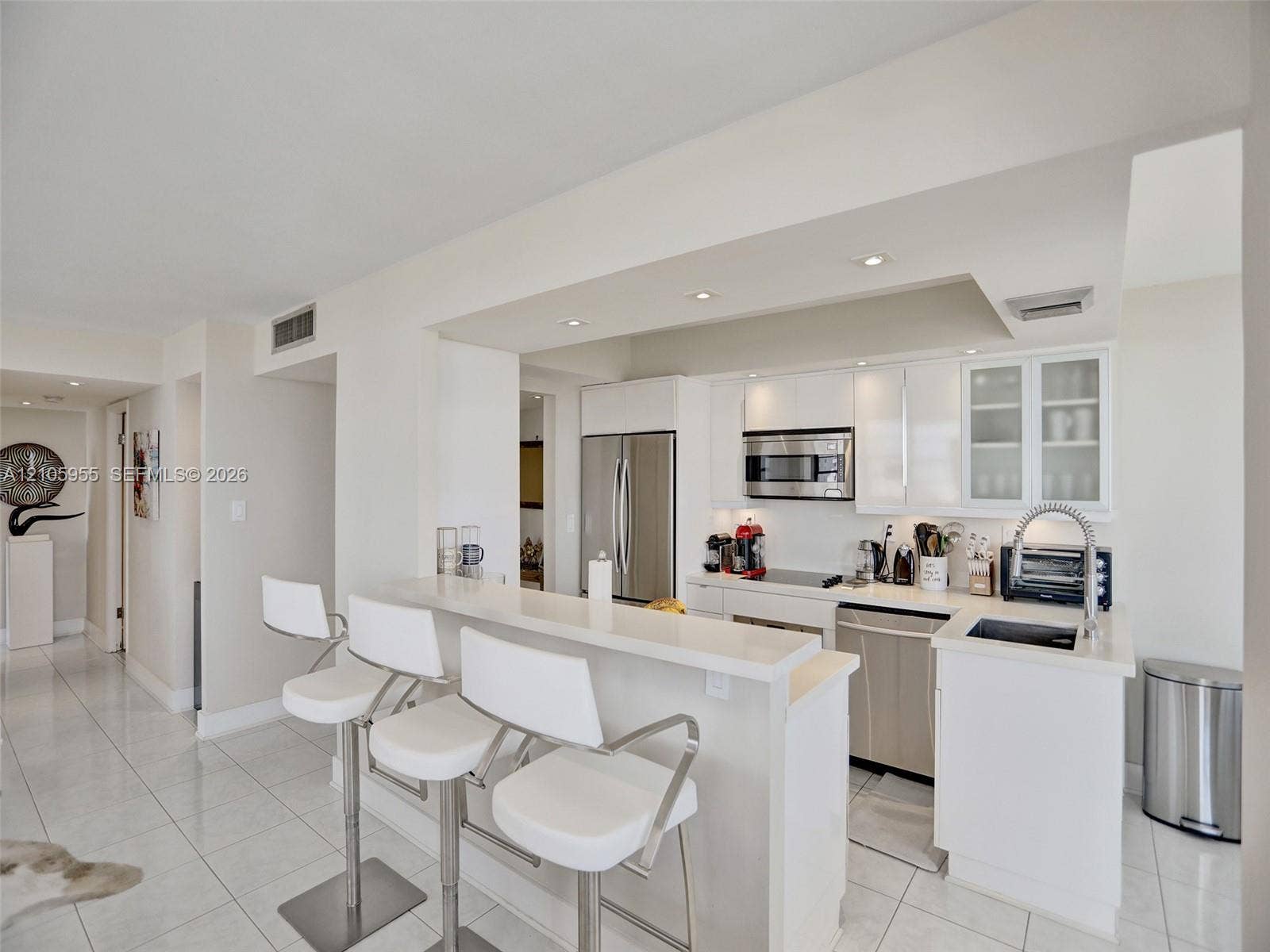 18011 Biscayne Boulevard, #1904, Aventura, FL 33160 Kitchen featuring white cabinetry, quartz countertops, a peninsula with bar seating, stainless steel appliances, and tile flooring