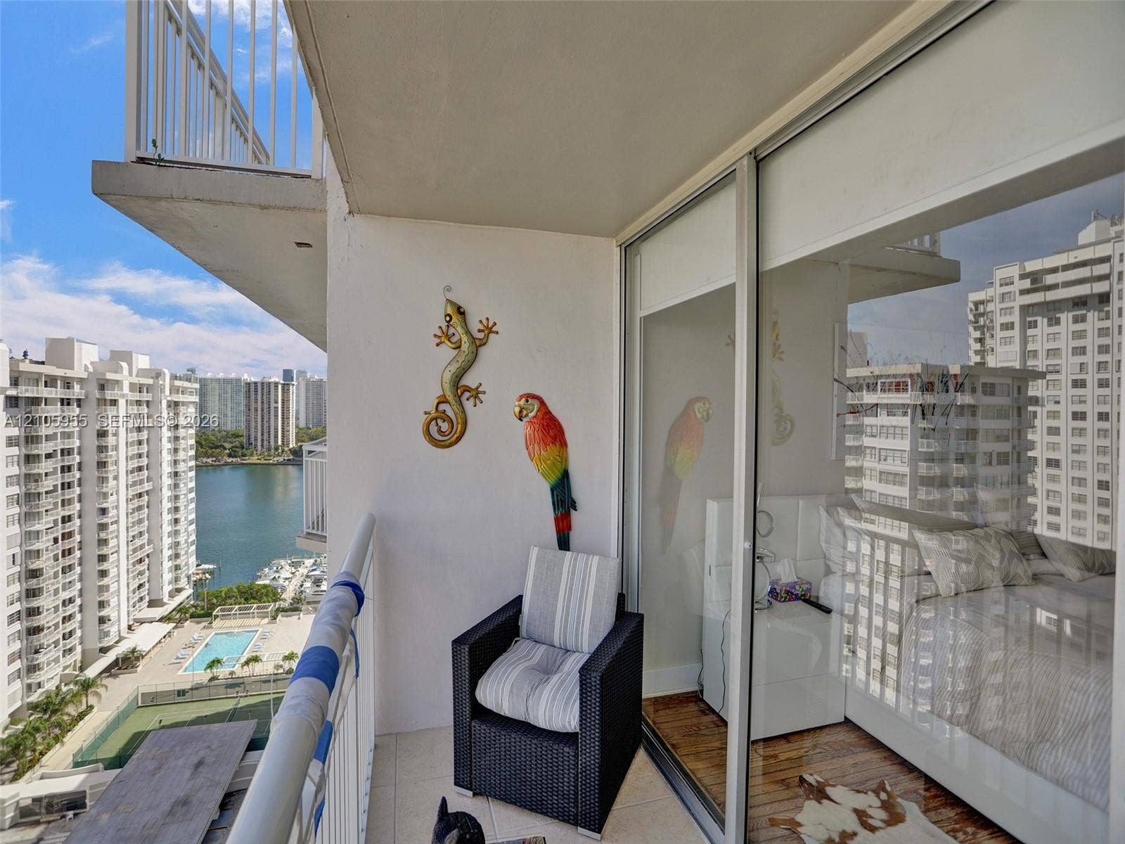 18011 Biscayne Boulevard, #1904, Aventura, FL 33160 Covered balcony featuring white tiled flooring and a metal railing, floor-to-ceiling sliding glass doors, and panoramic urban and water surroundings
