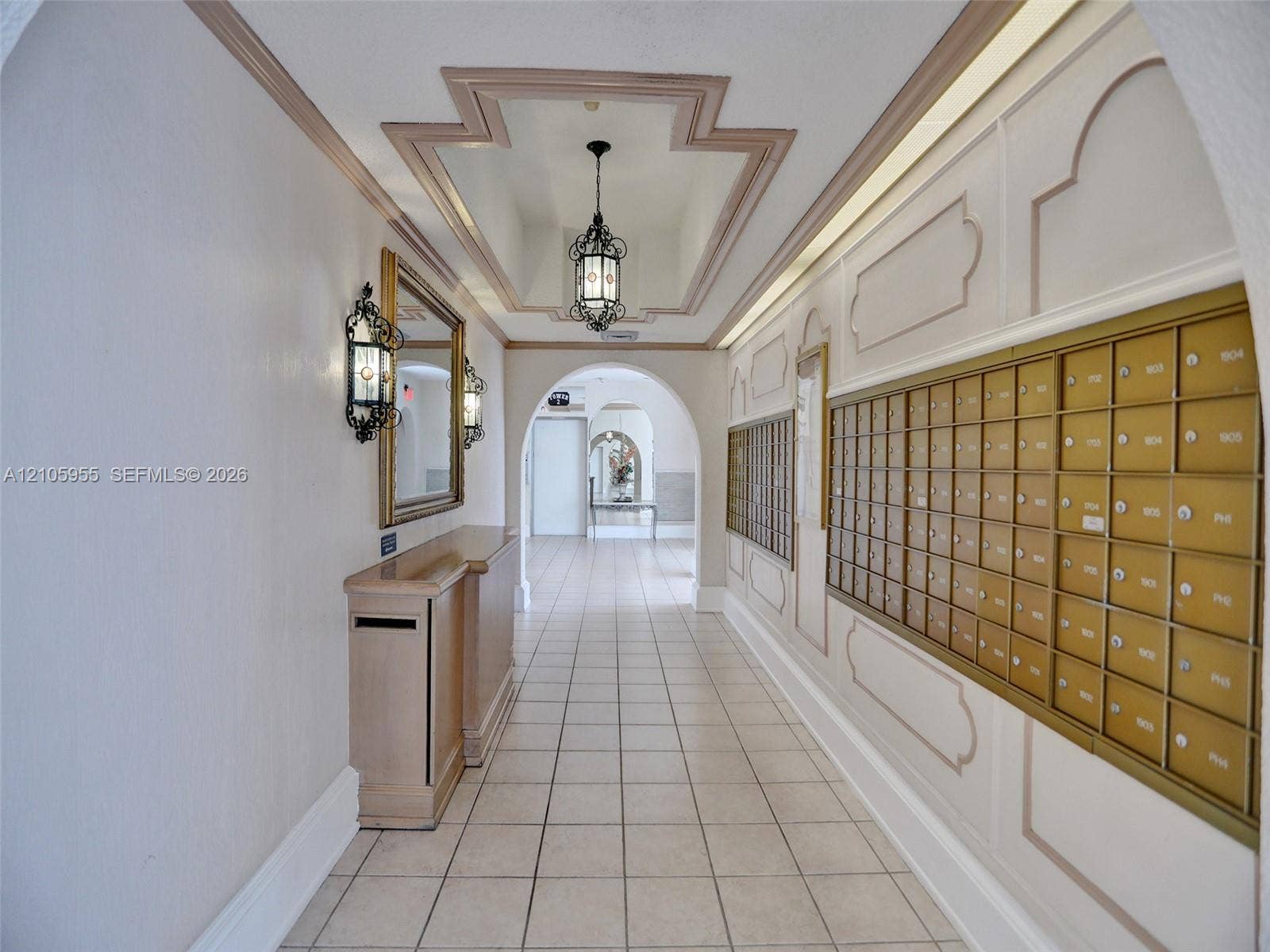18011 Biscayne Boulevard, #1904, Aventura, FL 33160 Entryway featuring ceramic tile flooring, built-in metal mailboxes, decorative wall molding, wrought-iron wall sconces, and a recessed ceiling design with a pendant fixture