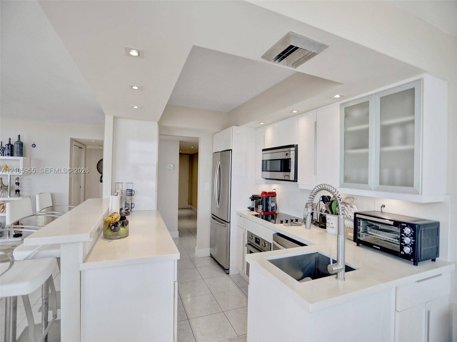 18011 Biscayne Boulevard, #1904, Aventura, FL 33160 Kitchen featuring white cabinetry, frosted glass cabinet doors, quartz countertops, stainless steel appliances, and tile flooring