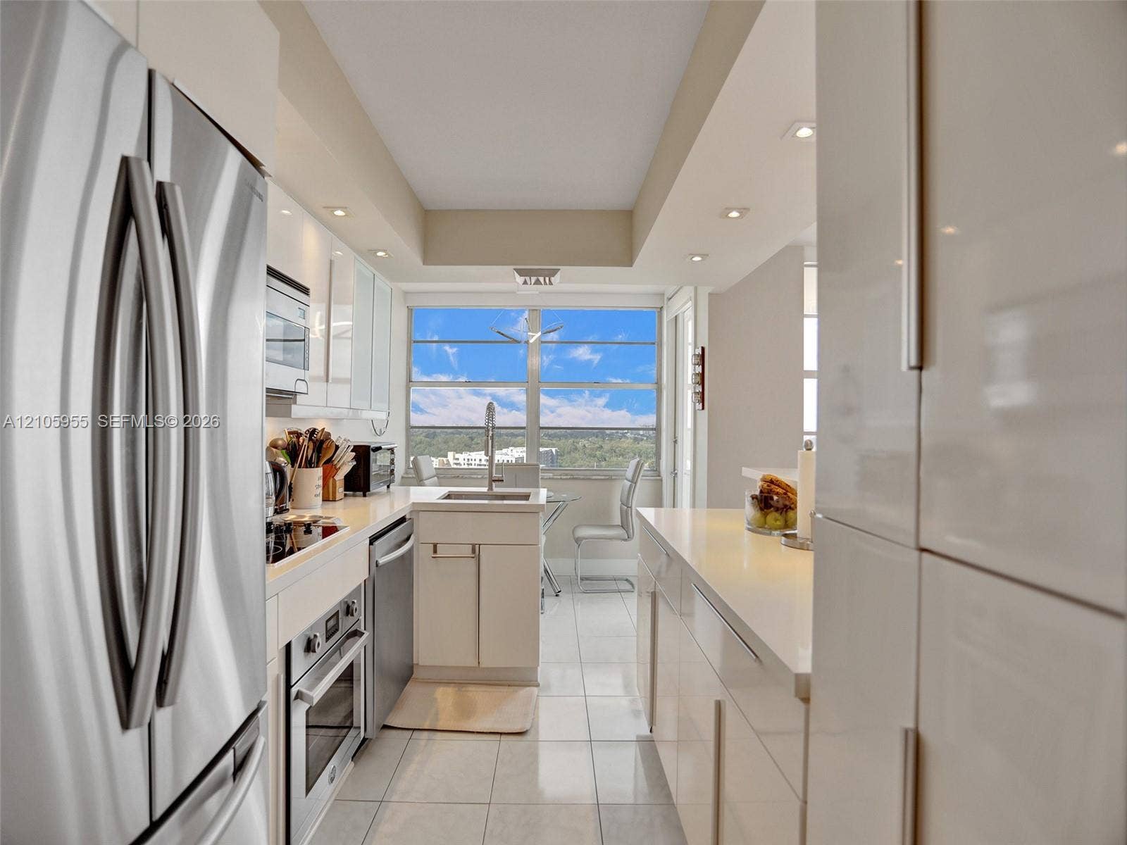 18011 Biscayne Boulevard, #1904, Aventura, FL 33160 Kitchen featuring high-gloss cabinetry, stainless steel appliances, solid-surface countertops, tile flooring, and large window