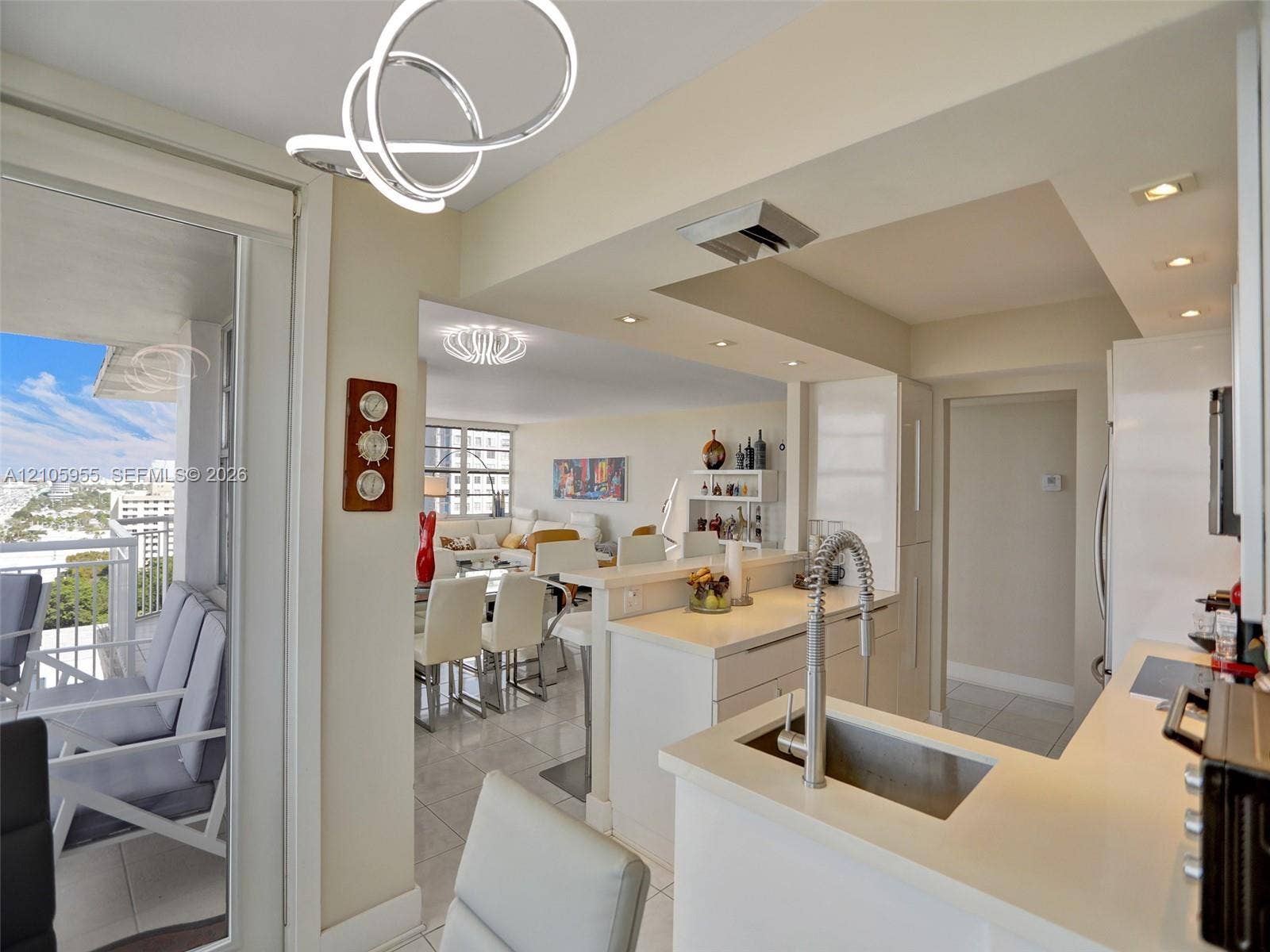 18011 Biscayne Boulevard, #1904, Aventura, FL 33160 Kitchen featuring a peninsula with a stone-finish countertop, stainless steel undermount sink with a high-arch pull-down faucet, recessed lighting, and sleek white cabinetry
