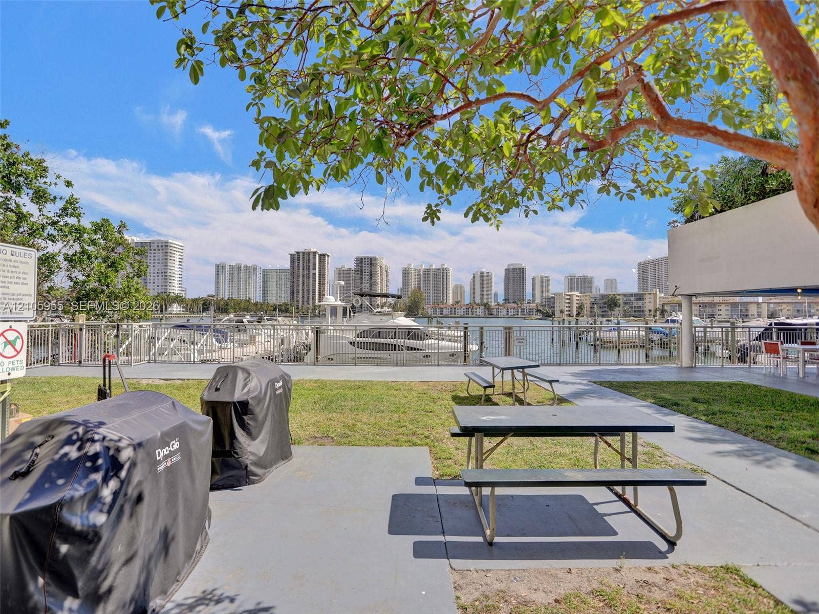 18011 Biscayne Boulevard, #1904, Aventura, FL 33160 Waterfront grounds featuring a concrete patio, grassy lawn, metal perimeter fencing, and access to boat slips