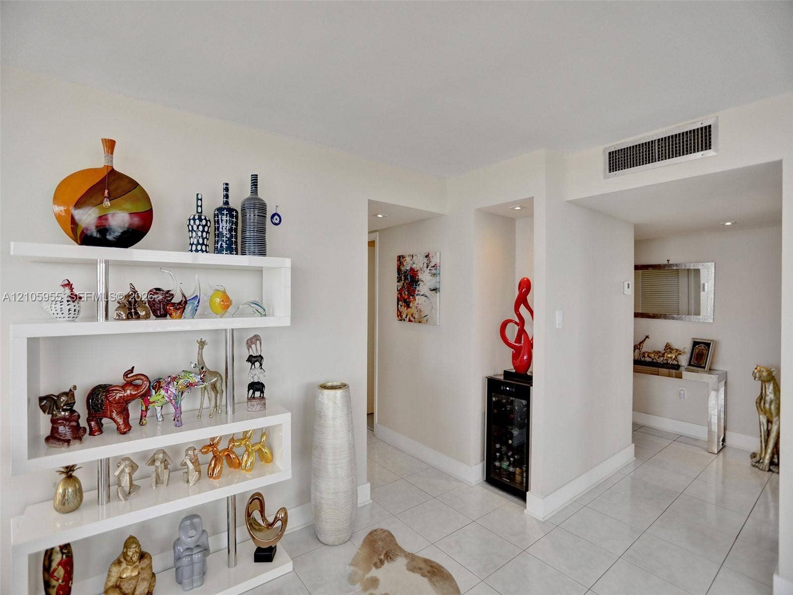 18011 Biscayne Boulevard, #1904, Aventura, FL 33160 Glossy tile flooring, custom white built-in display shelving, and a recessed beverage refrigerator