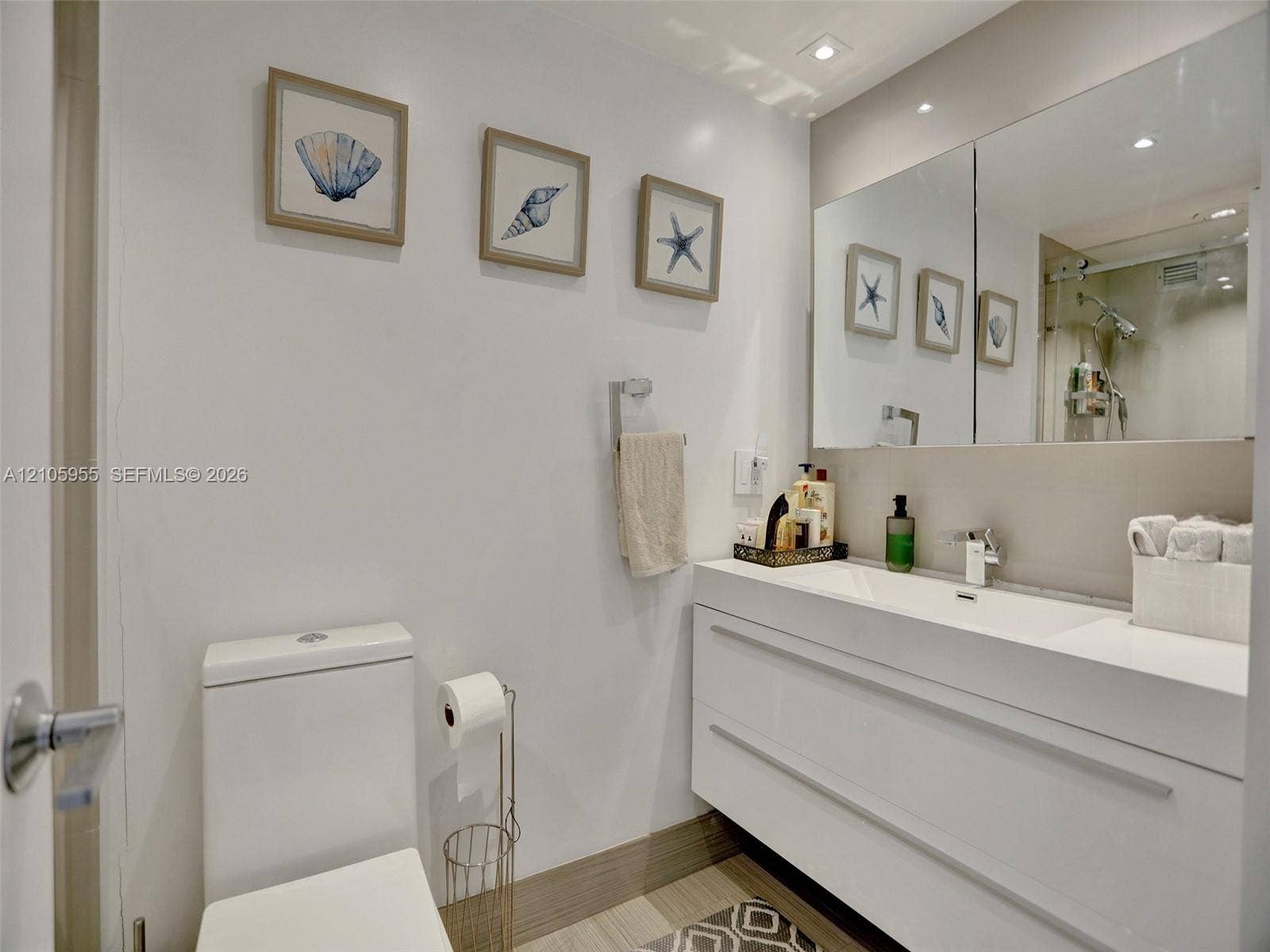 18011 Biscayne Boulevard, #1904, Aventura, FL 33160 Modern floating vanity featuring an integrated white sink and basin, chrome faucet, expansive wall-to-wall mirror, and recessed lighting