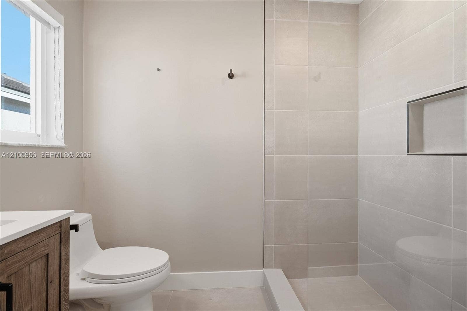 1154 Croton Court, Weston, Weston, FL 33327 Wood-finish vanity, white countertop, walk-in shower with large-format wall tile, glass partition, and recessed shower niche