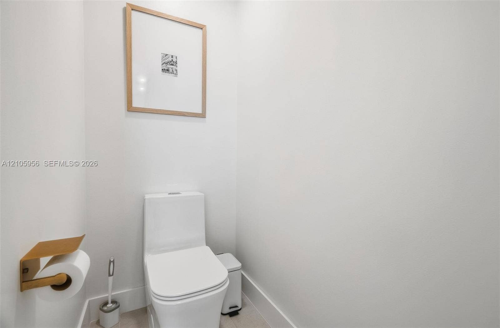 1154 Croton Court, Weston, Weston, FL 33327 Minimalist powder room featuring a white dual-flush elongated toilet and a wall-mounted metallic gold finish toilet paper holder