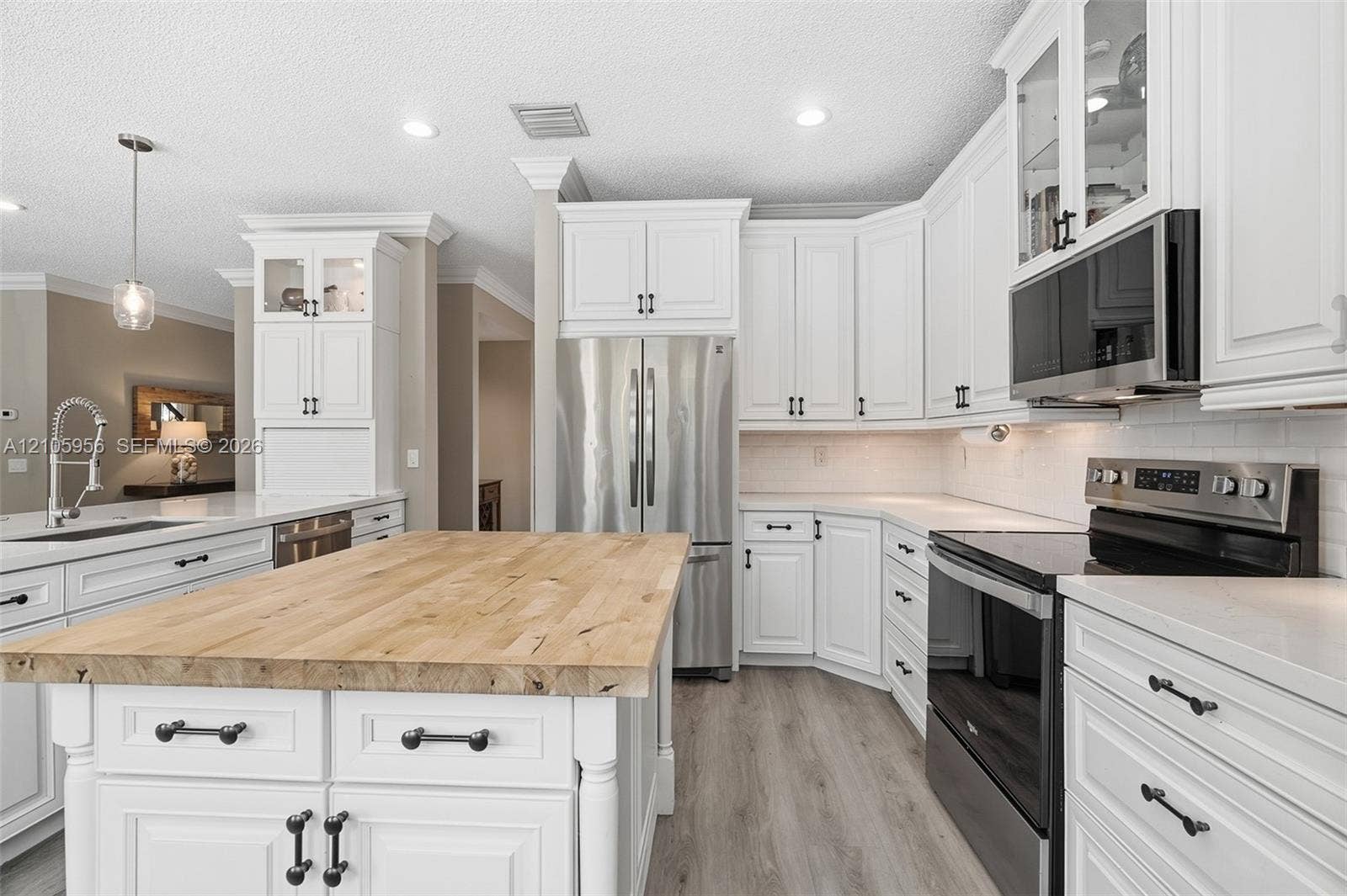 1154 Croton Court, Weston, Weston, FL 33327 Kitchen featuring white shaker-style cabinetry, wood-top center island, stainless steel appliances, light-toned countertop surfaces, and wood-finish flooring