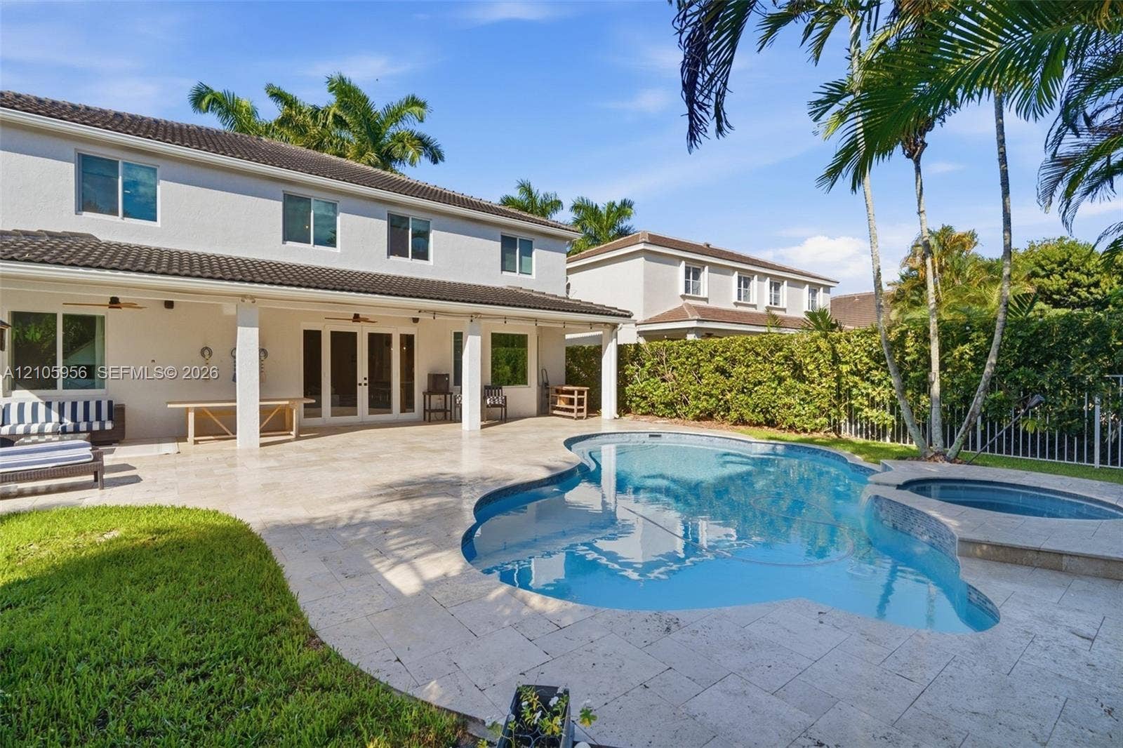 1154 Croton Court, Weston, Weston, FL 33327 Covered concrete patio with multi-panel glass doors, stone-tiled pool deck, and an integrated spa