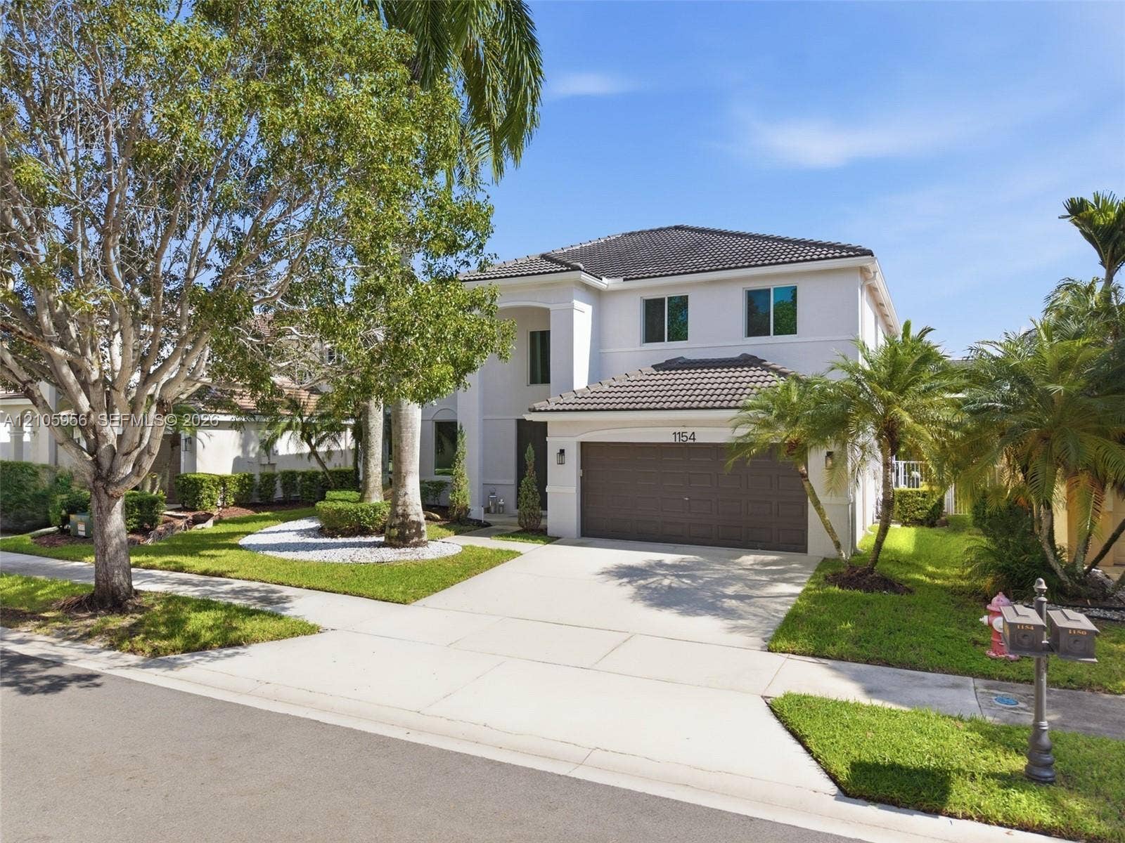 1154 Croton Court, Weston, Weston, FL 33327 Two-story stucco exterior featuring a concrete tile roof, attached two-car garage, and mature professional landscaping