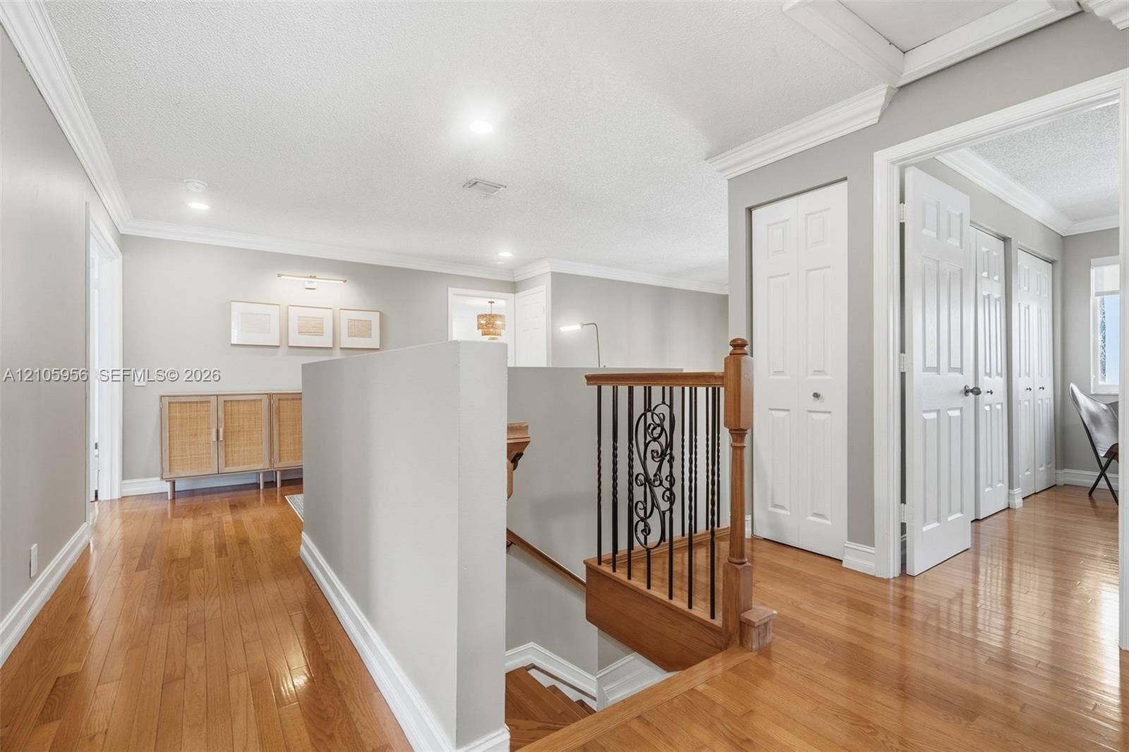 1154 Croton Court, Weston, Weston, FL 33327 Wood-finish flooring, decorative wrought iron balusters with a wooden handrail, crown molding, and multi-panel interior doors