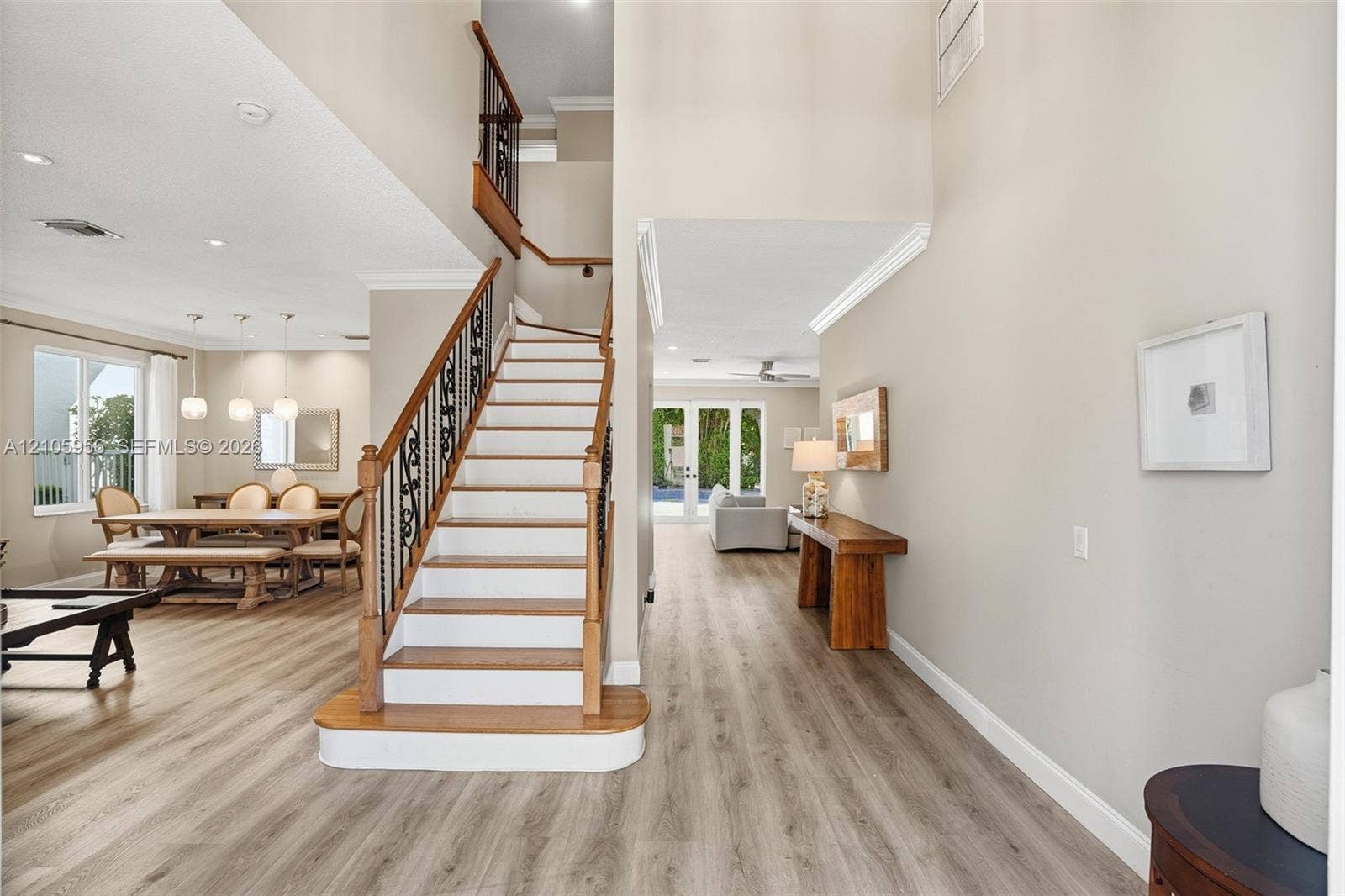1154 Croton Court, Weston, Weston, FL 33327 Open-concept interior featuring wood-finish flooring, a grand staircase with decorative metal balusters and wood handrails, high ceilings, recessed lighting, and crown molding