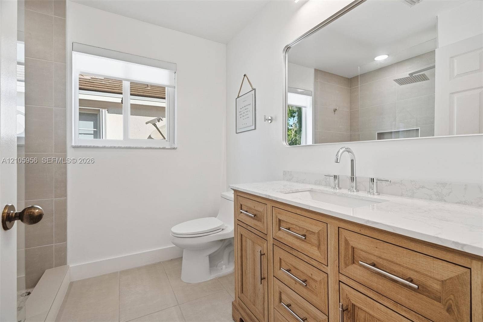 1154 Croton Court, Weston, Weston, FL 33327 Bathroom featuring a natural wood-finish vanity with stone-look countertop, rectangular undermount sink, large wall-mounted mirror, and tile-surround shower with rain showerhead