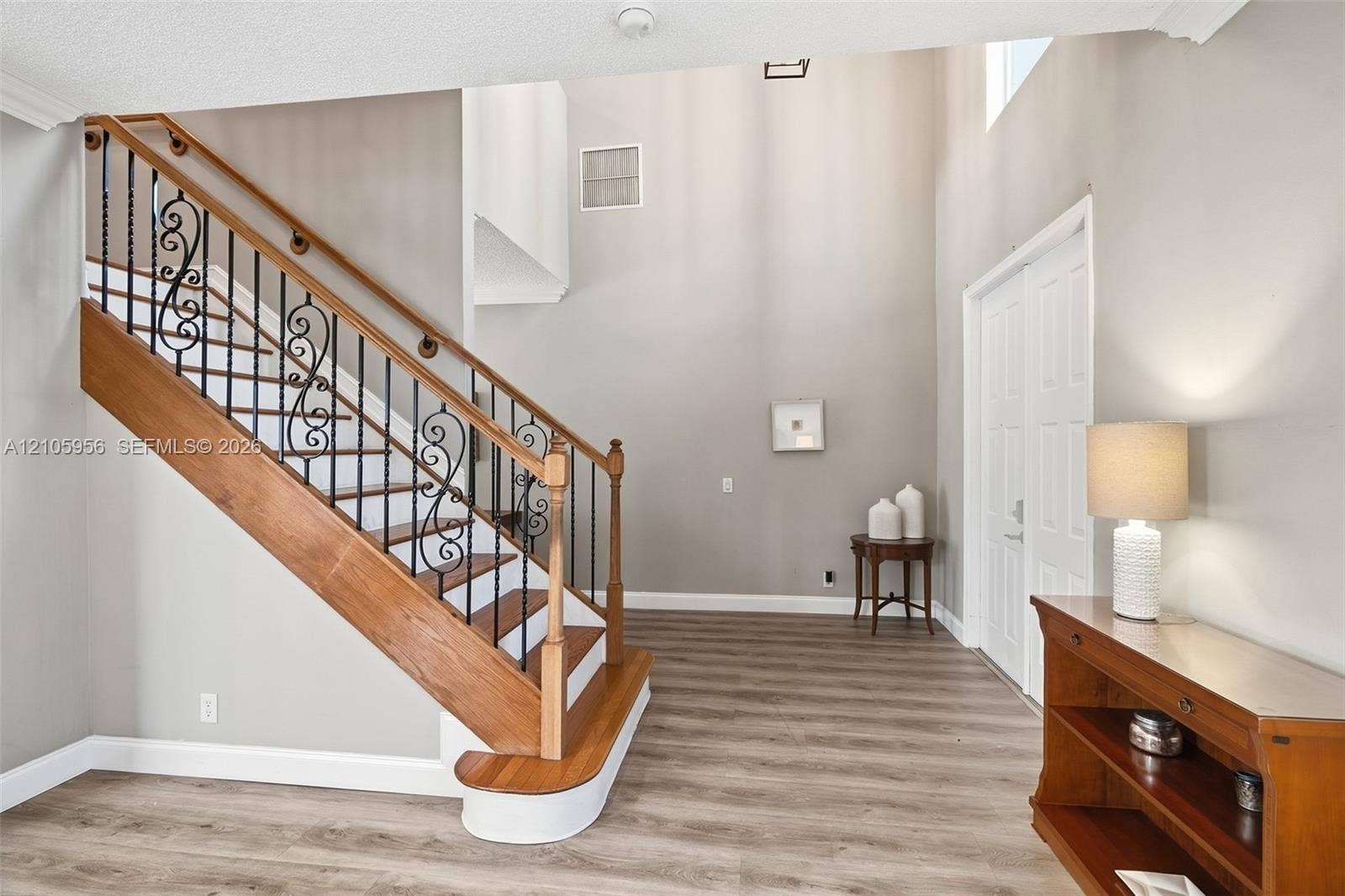 1154 Croton Court, Weston, Weston, FL 33327 Two-story foyer featuring high ceilings, wood-finish flooring, and a staircase with decorative wrought-iron balusters and a natural wood handrail