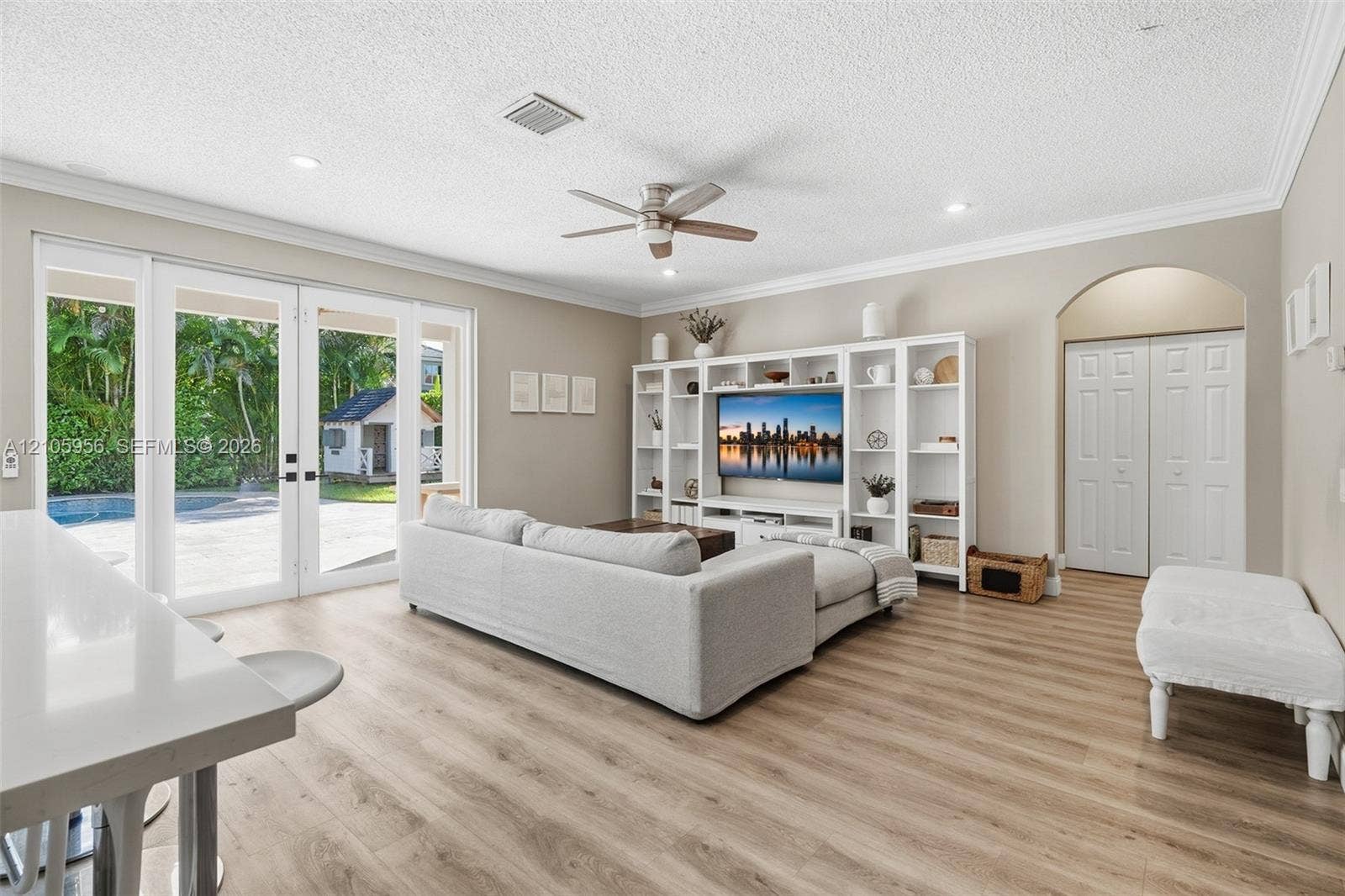 1154 Croton Court, Weston, Weston, FL 33327 Living area featuring wood-finish flooring, crown molding, recessed lighting, built-in floor-to-ceiling shelving, and multi-panel glass patio doors