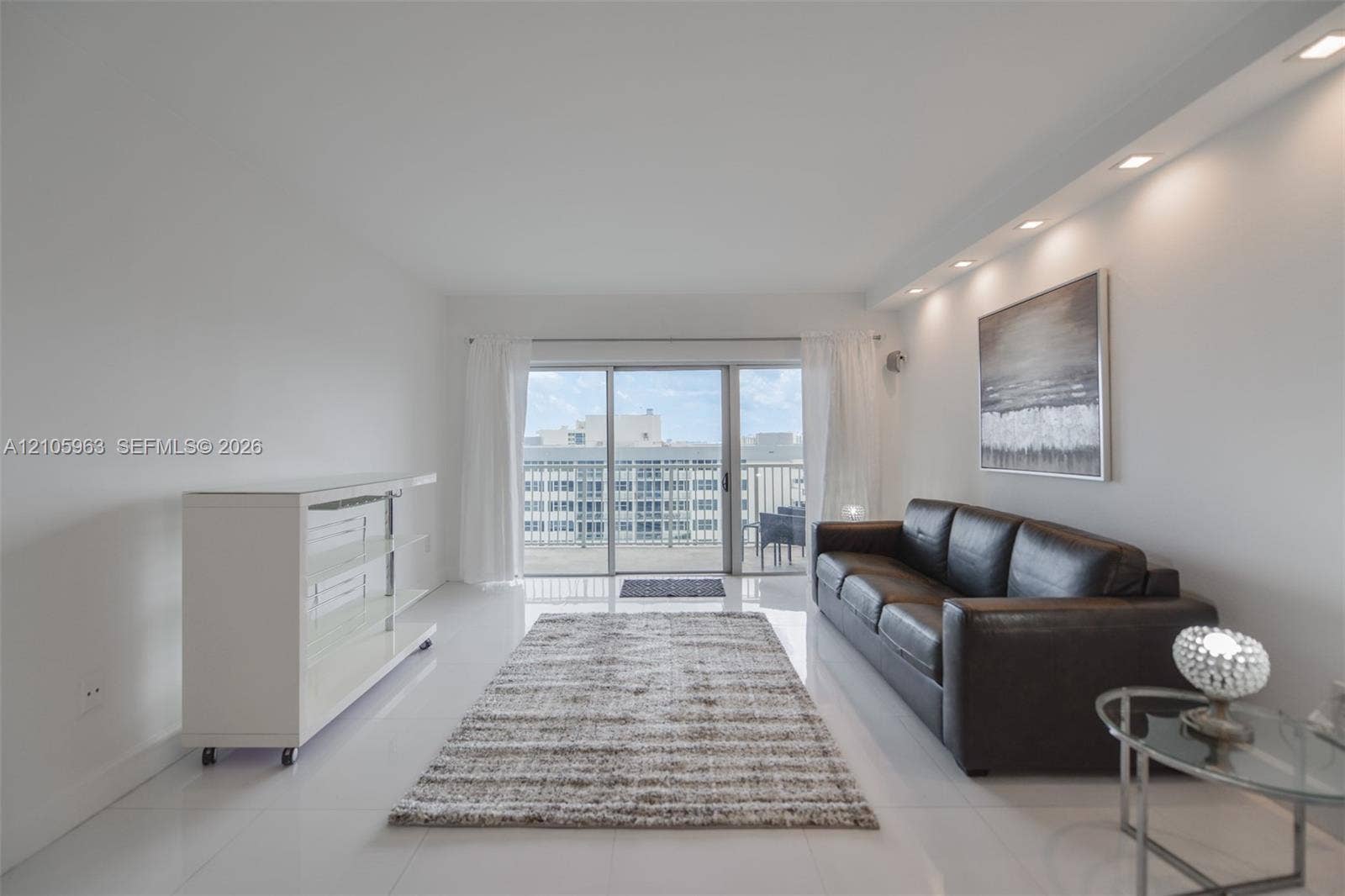 1980 S Ocean Drive, #PHA, Hallandale Beach, Hallandale Beach, FL 33009 Open-concept living space featuring high-gloss tile flooring, recessed cove lighting, and floor-to-ceiling sliding glass doors providing access to an outdoor balcony