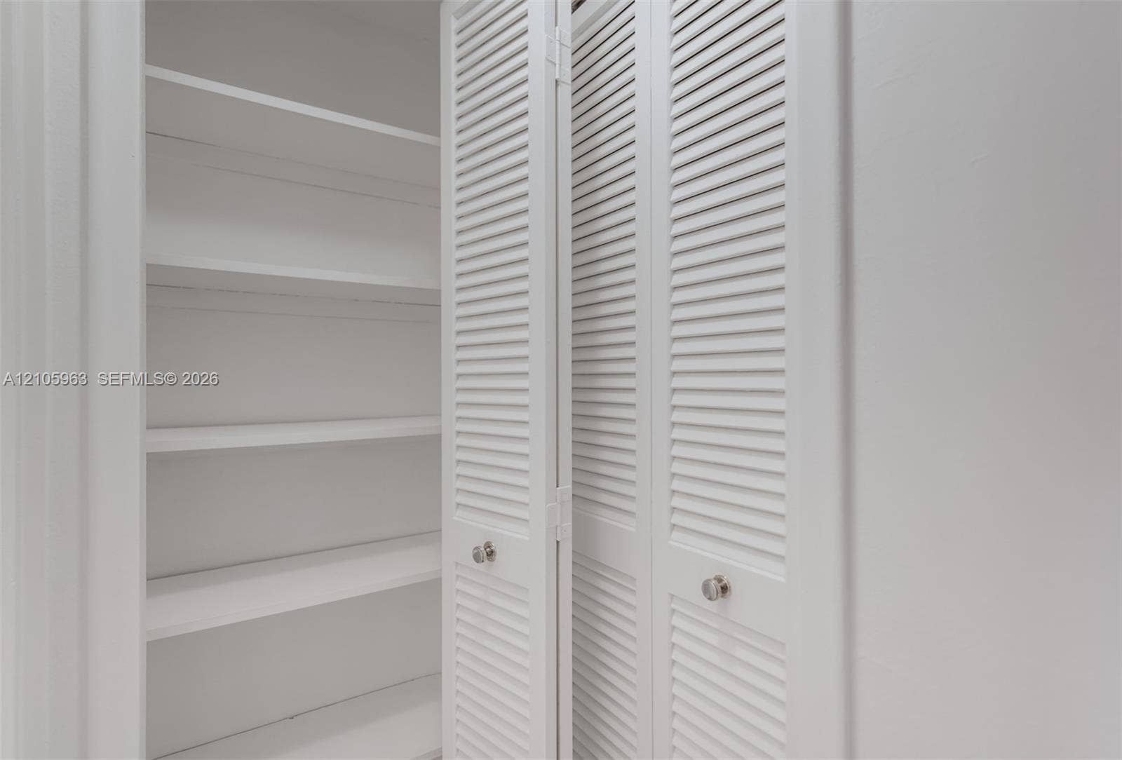 1980 S Ocean Drive, #PHA, Hallandale Beach, Hallandale Beach, FL 33009 Storage closet featuring white louvered bifold doors, chrome round knobs, and interior shelving