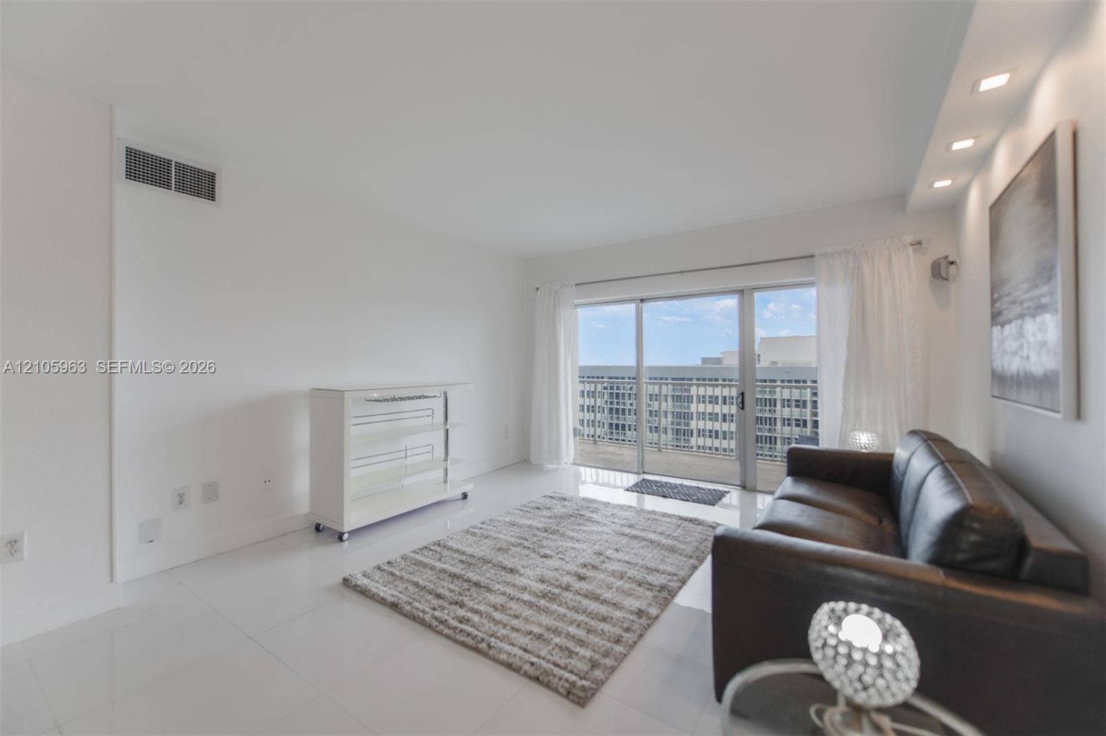 1980 S Ocean Drive, #PHA, Hallandale Beach, Hallandale Beach, FL 33009 Living space featuring white tile flooring, recessed ceiling lighting, and sliding glass doors with access to an exterior balcony
