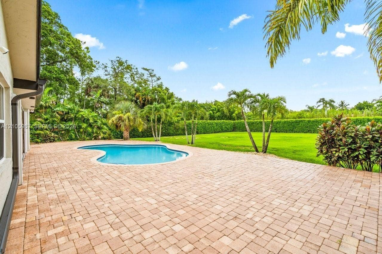 5966 NW 77th Terrace, Parkland, Parkland, FL 33067 Backyard featuring a paver patio, a free-form pool, a manicured lawn, and mature palm trees