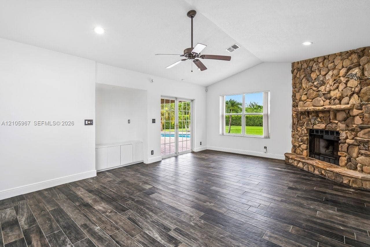 5966 NW 77th Terrace, Parkland, Parkland, FL 33067 Vaulted ceilings, wood-finish flooring, floor-to-ceiling natural stone fireplace, built-in cabinetry, and sliding glass doors