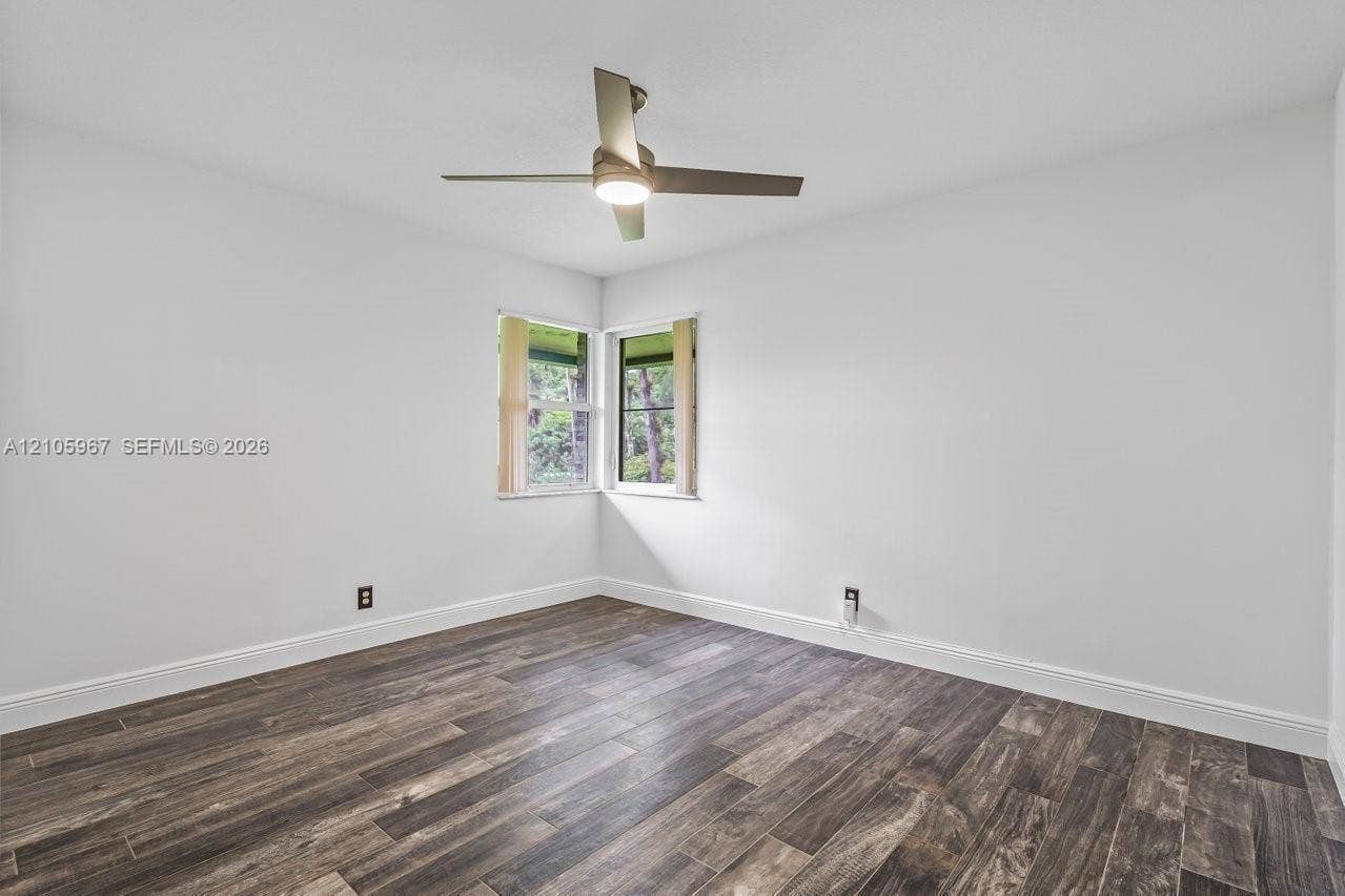 5966 NW 77th Terrace, Parkland, Parkland, FL 33067 Room featuring wood-finish flooring, white walls, corner windows, and a ceiling-mounted light fixture with fan
