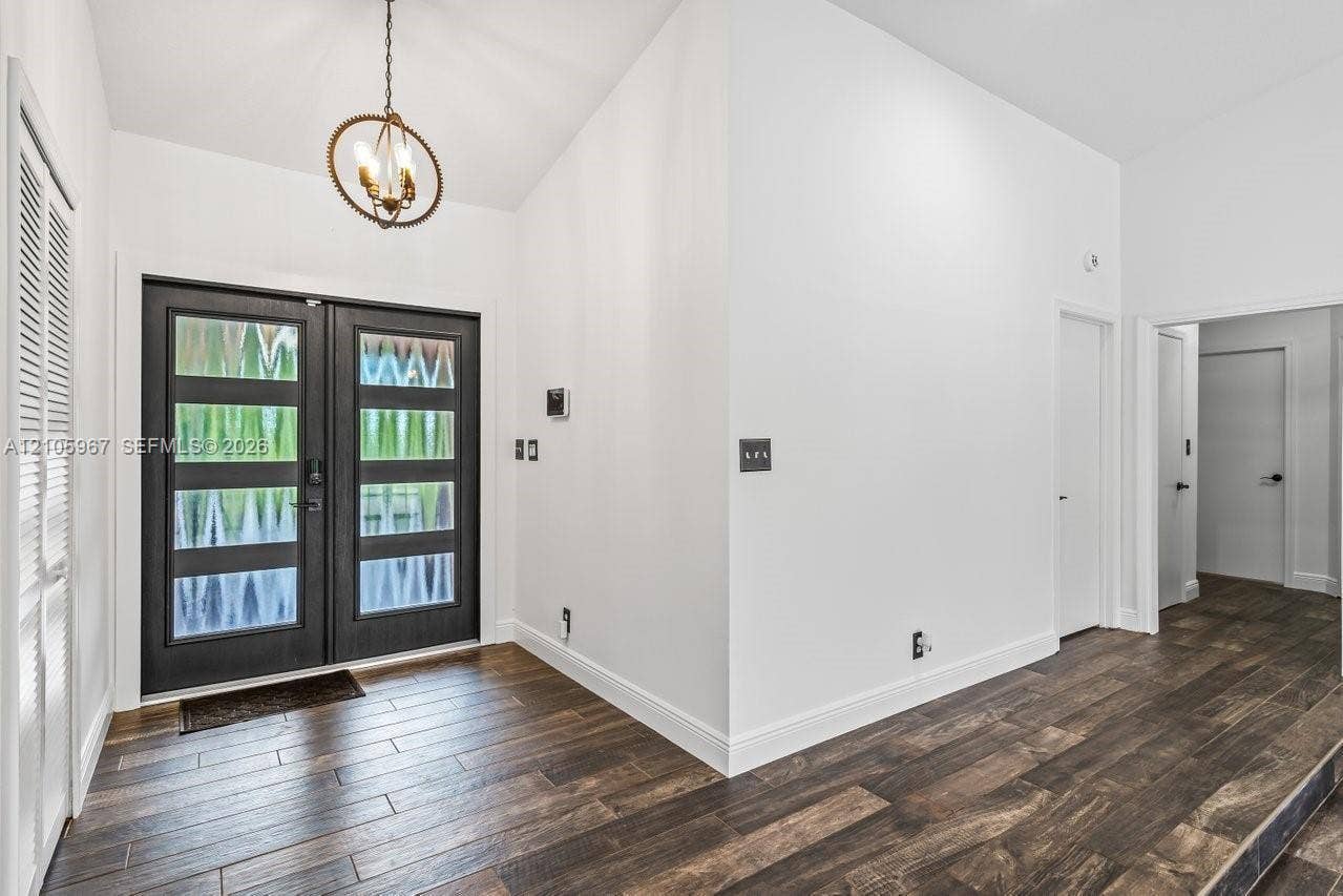 5966 NW 77th Terrace, Parkland, Parkland, FL 33067 Double-door entry with glass panels, wood-finish flooring, and a circular orb-style chandelier
