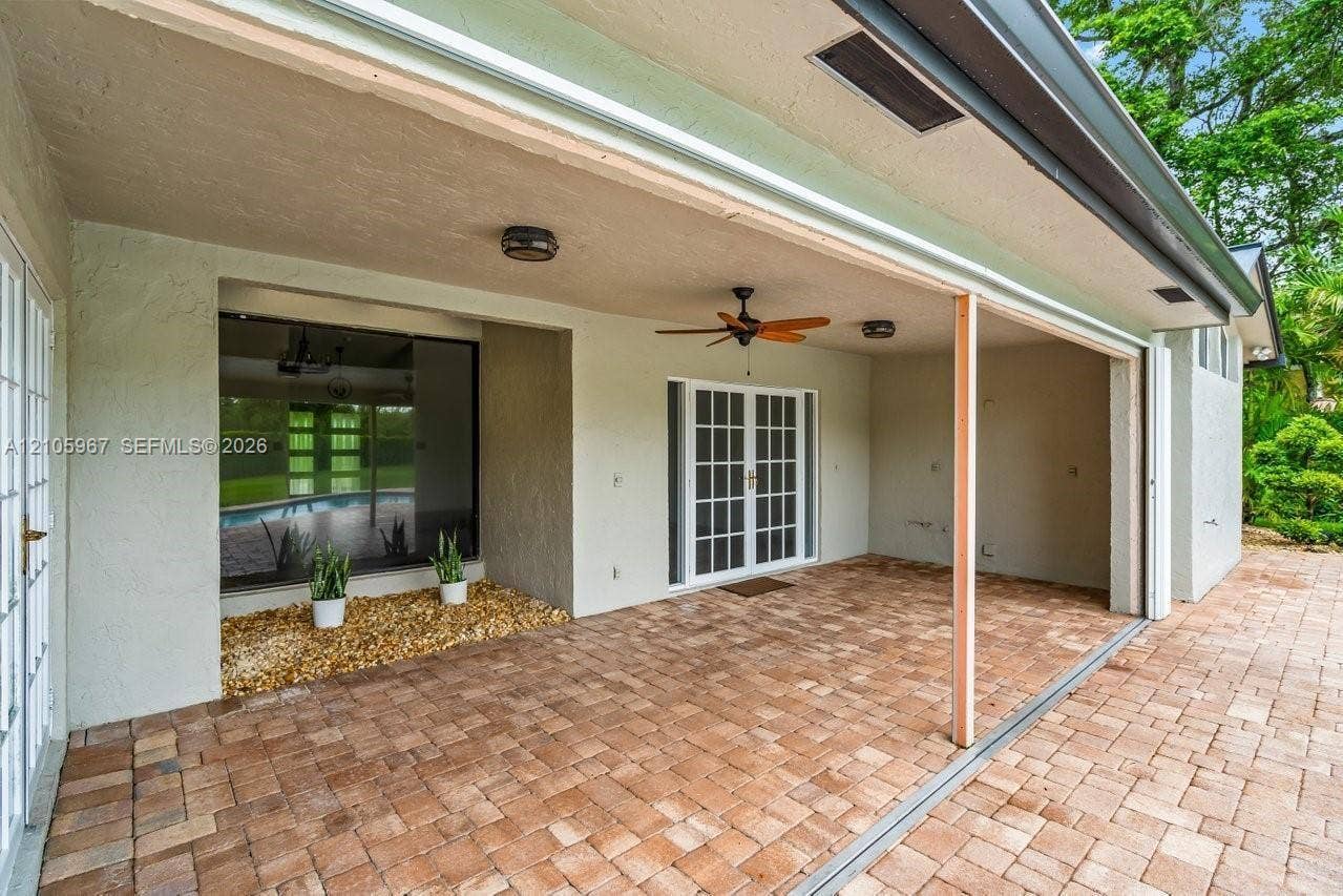 5966 NW 77th Terrace, Parkland, Parkland, FL 33067 Covered patio featuring concrete paver flooring, French doors, ceiling fan, and built-in stone landscaping bed