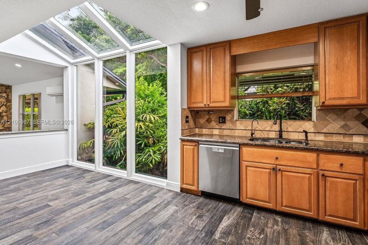 5966 NW 77th Terrace, Parkland, Parkland, FL 33067 Kitchen featuring floor-to-ceiling windows with integrated skylights, wood-finish cabinetry, stone-surface countertops, stone tile backsplash, and wood-finish flooring