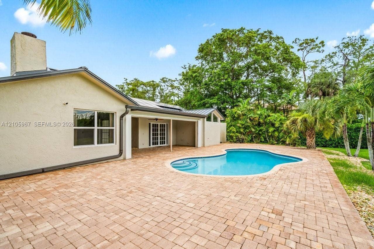 5966 NW 77th Terrace, Parkland, Parkland, FL 33067 Backyard featuring a paved patio, a freeform swimming pool with integrated steps, a covered lanai, and mature landscape