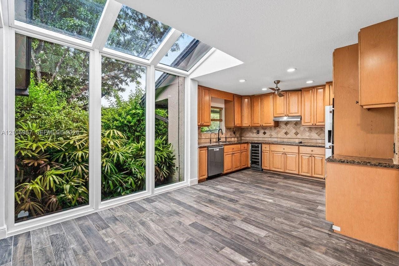 5966 NW 77th Terrace, Parkland, Parkland, FL 33067 Kitchen featuring full-height glass walls and sloped skylights, wood-finish flooring, shaker-style cabinetry, and integrated wine refrigeration