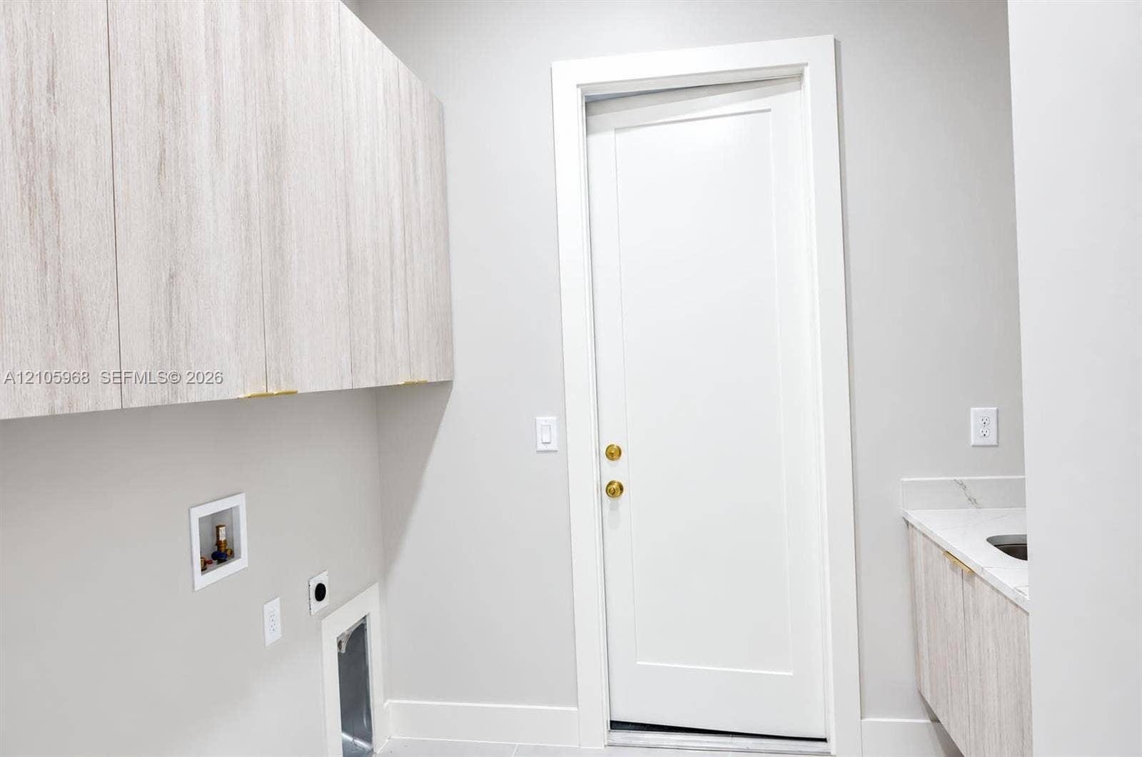 3509 63rd Street W, Lehigh Acres, FL 33971 Wall-mounted wood-finish cabinetry, solid-core shaker-style door with brass hardware, stone-surface countertop, and built-in basin
