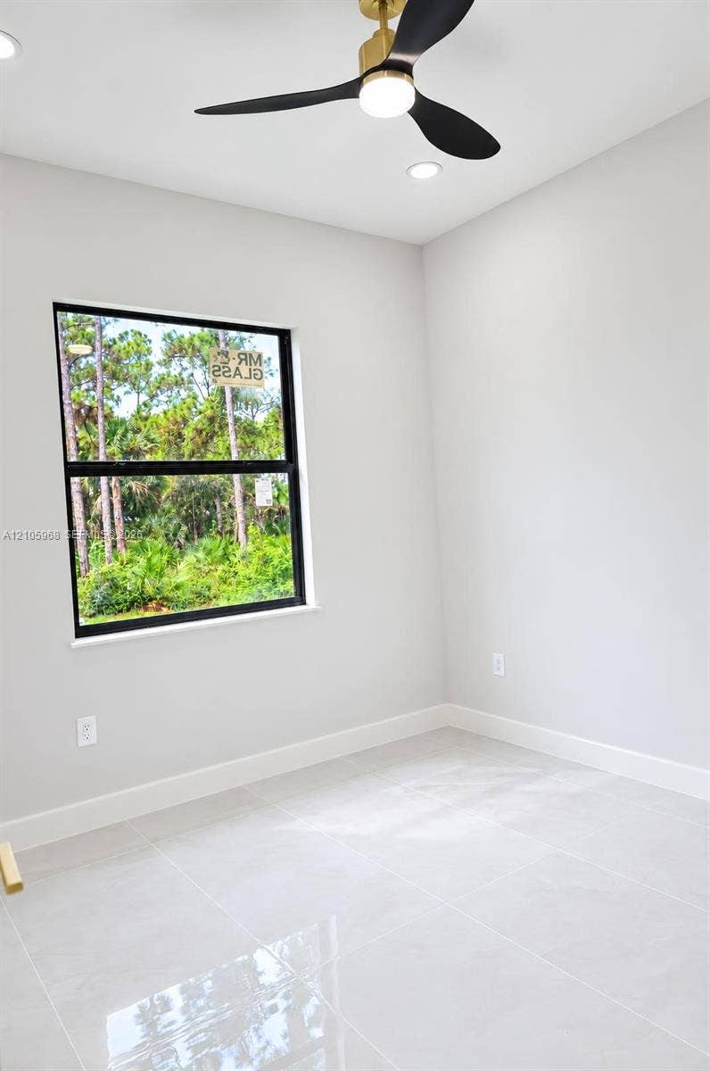 3509 63rd Street W, Lehigh Acres, FL 33971 Interior space featuring large-format tile flooring, a modern three-blade ceiling fan with integrated light, recessed lighting, and a window with a black frame