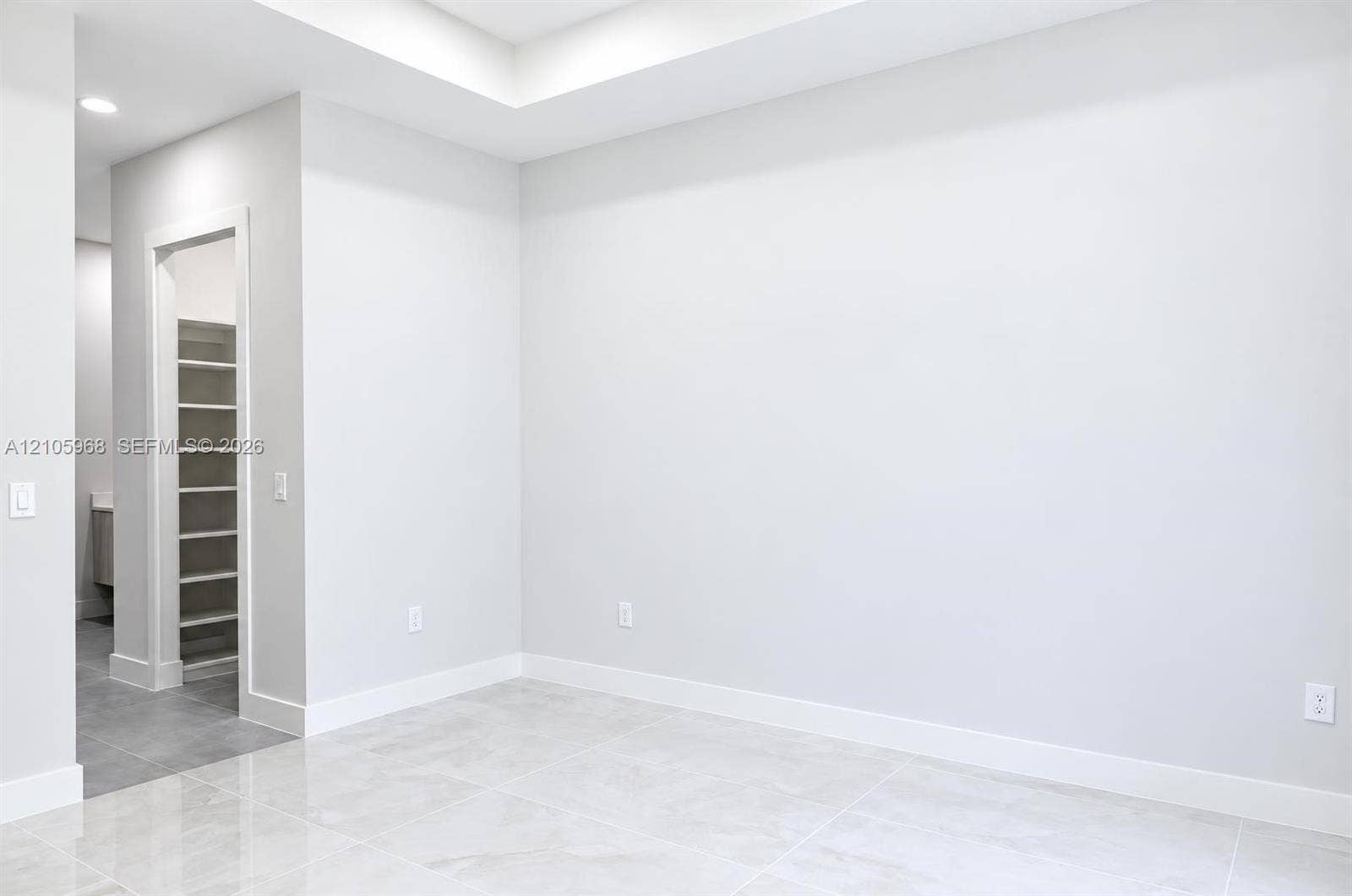 3509 63rd Street W, Lehigh Acres, FL 33971 Tray ceiling, recessed lighting, and large-format tile flooring, featuring a walk-in storage area with custom shelving