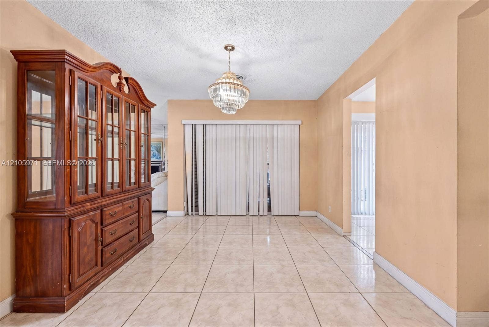 6604 Coconut Drive, Miramar, FL 33023 Large-format neutral tile flooring throughout, multi-tiered crystal pendant light fixture, and floor-to-ceiling vertical window blinds