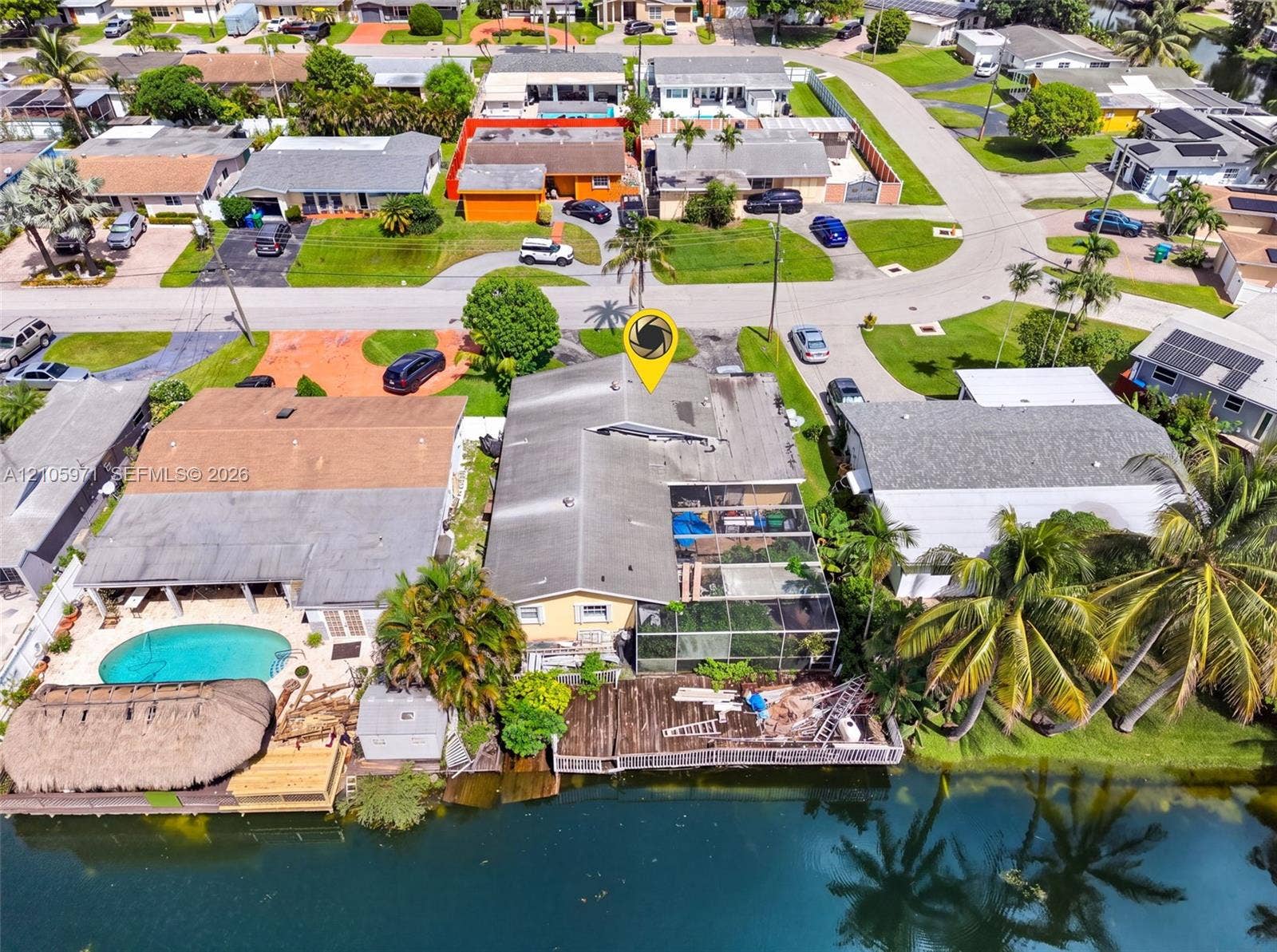 6604 Coconut Drive, Miramar, FL 33023 Waterfront property featuring a screened-in lanai, private dock, and established palm trees