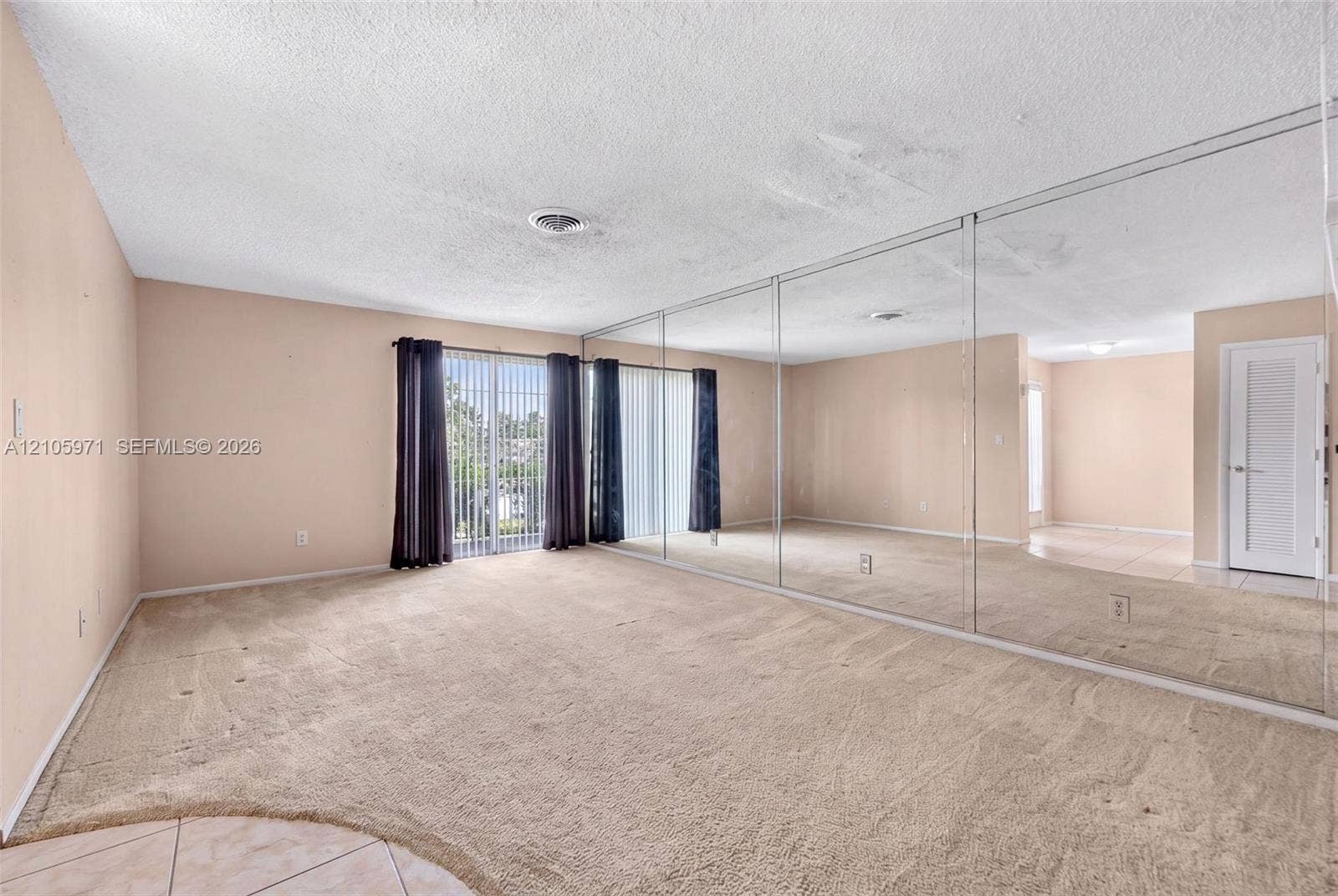 6604 Coconut Drive, Miramar, FL 33023 Floor-to-ceiling wall mirrors, sliding glass door, carpeted flooring, and a multi-panel interior door