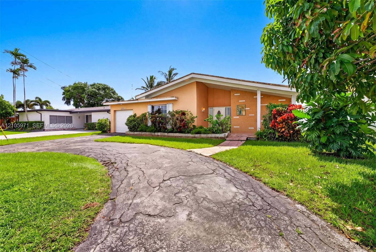 6604 Coconut Drive, Miramar, FL 33023 Single-story exterior featuring a stucco facade, attached garage, curved driveway, and mature landscaping