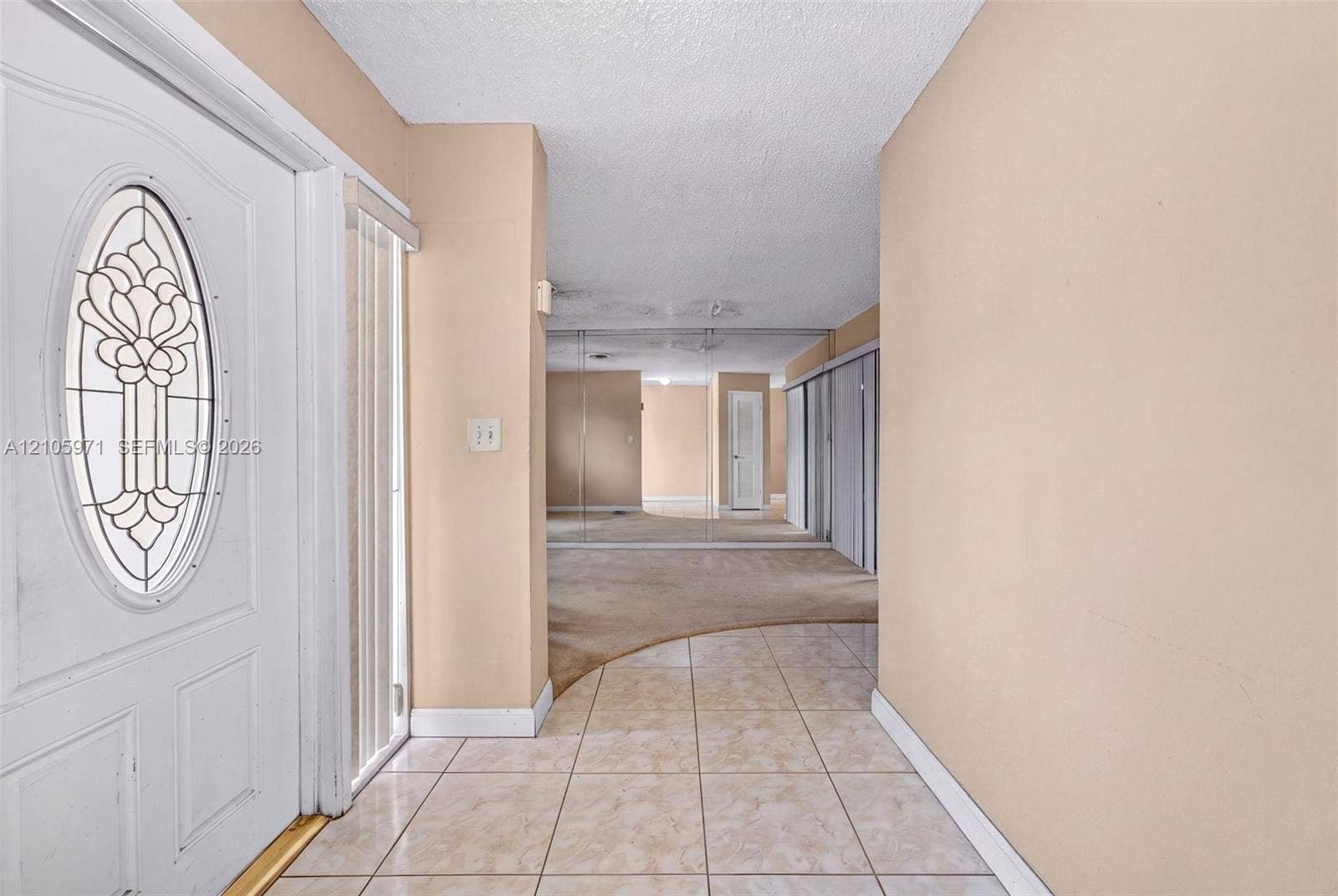 6604 Coconut Drive, Miramar, FL 33023 Entryway featuring a white door with an oval decorative glass insert, ceramic tile flooring, and wall-to-wall mirrored closet doors
