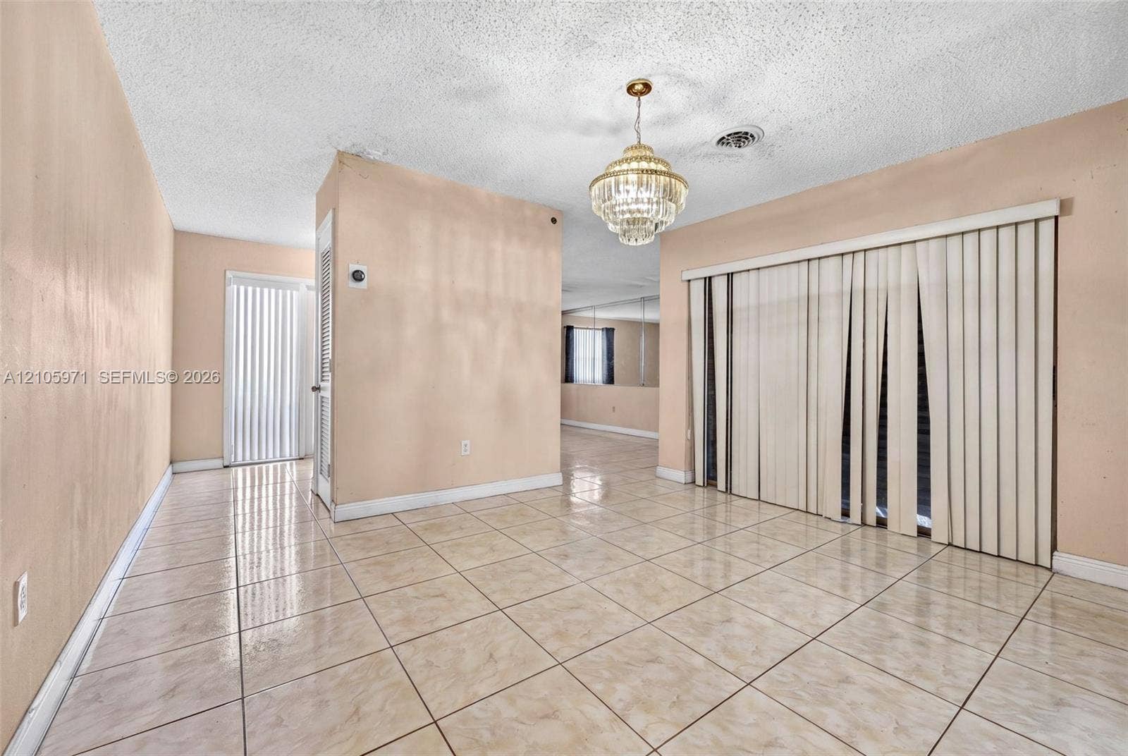 6604 Coconut Drive, Miramar, FL 33023 Ceramic tile flooring, tiered crystal chandelier, sliding glass door with vertical blinds, and wall-mounted mirror paneling